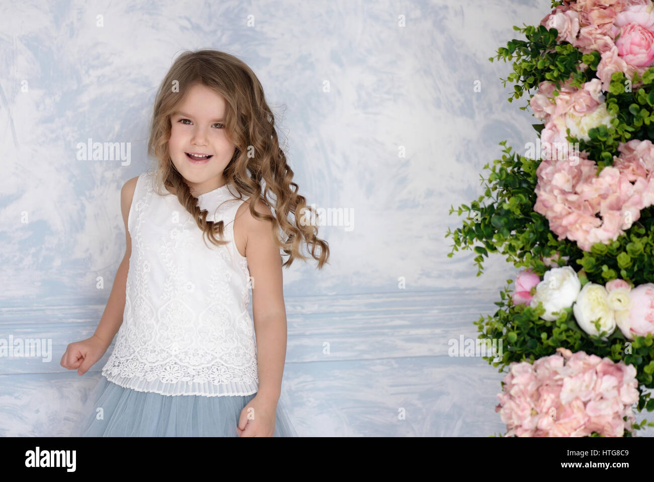 Kleines Mädchen Lachen im blauen Kleid mit Blumen. Herzlichen Glückwunsch oder glücklich Ferienkonzept. Stockfoto