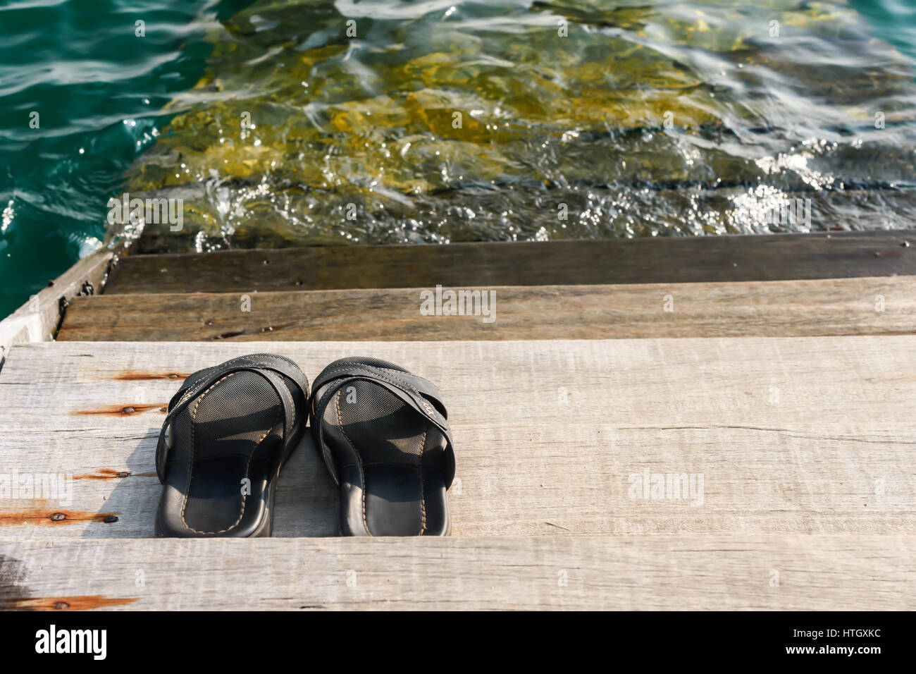 schwarze Herren Sandalen flip flop auf ein Brett im waterfront Stockfoto