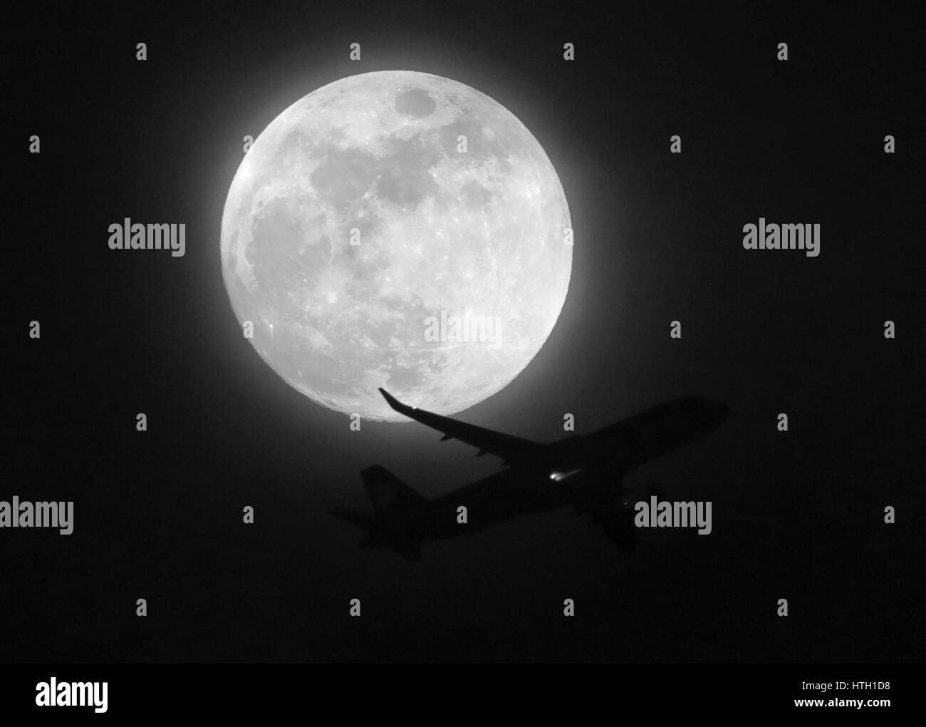 Ein Flugzeug fliegt vorbei ein waxing Crescent Moon, in Süd-London. Stockfoto