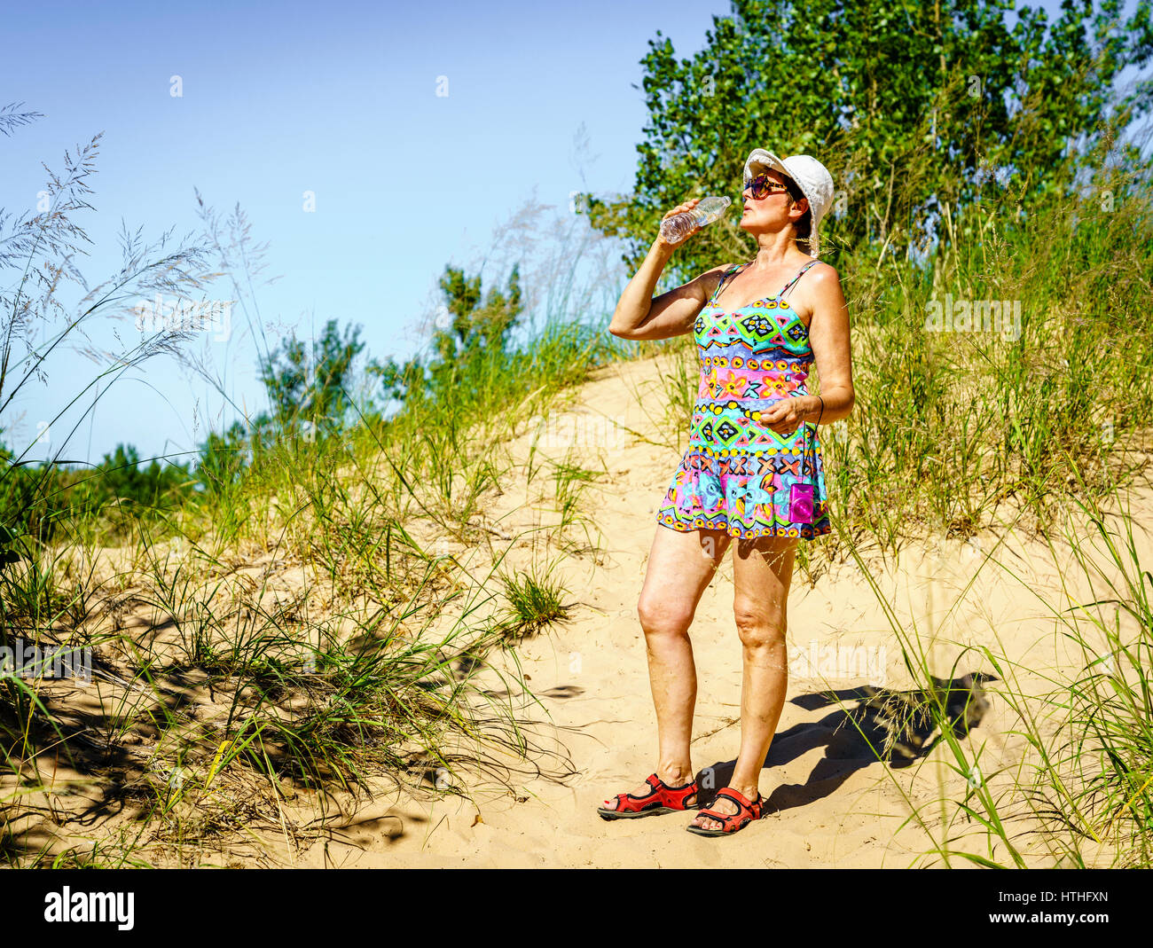 Frau ist Trinkwasser beim Wandern in den Dünen in Nord-Michigan Stockfoto