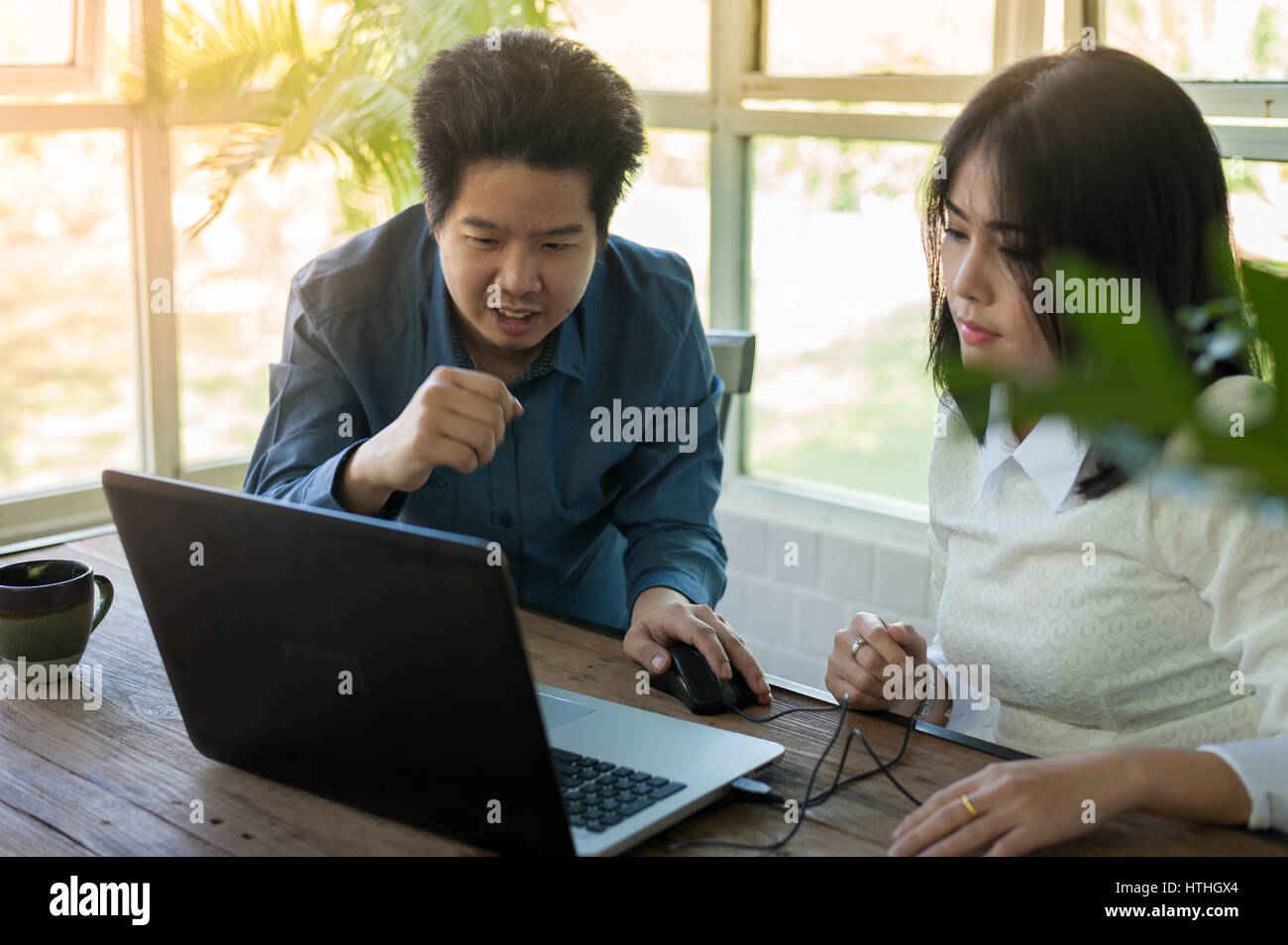 Junge asiatische Geschäftsmann und Geschäftsfrau sprechen über ihre Arbeit beim Laptop-Monitor im Café betrachten. Startup-Unternehmen für freie Arbeiten Stockfoto