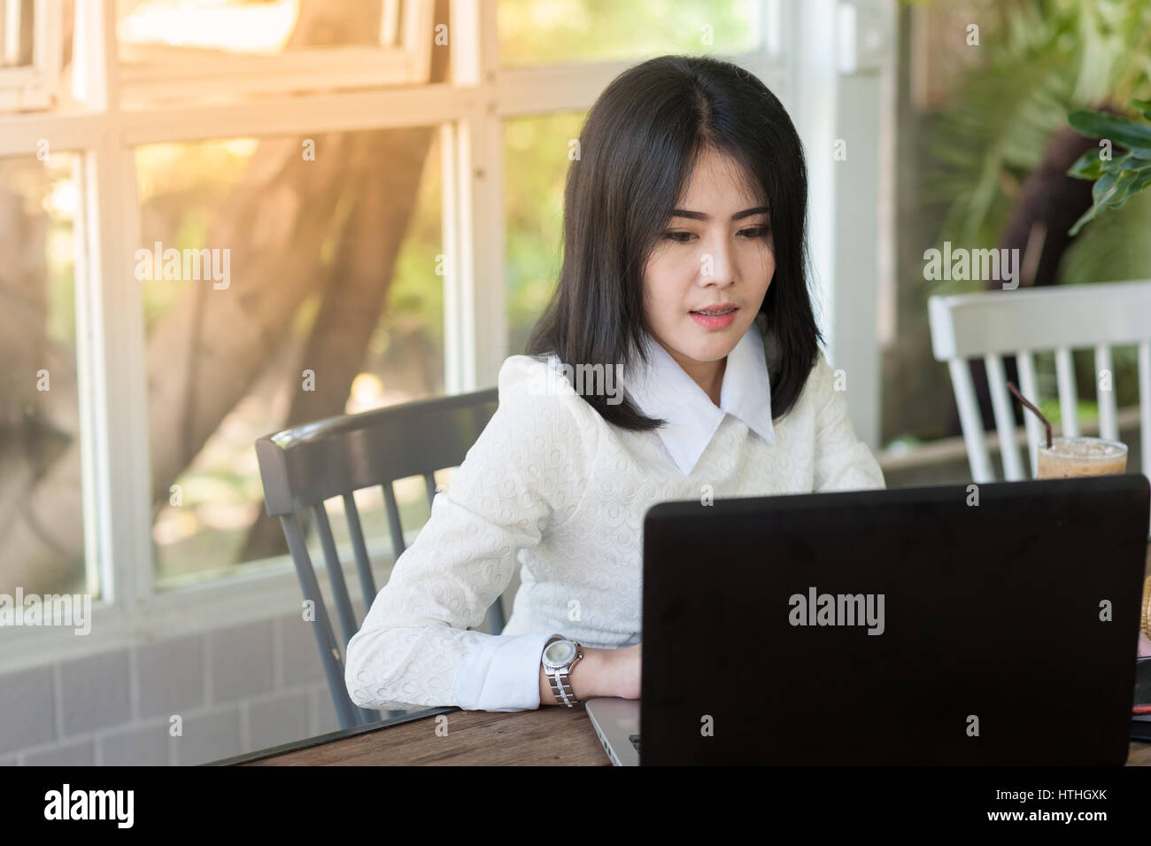 Junge asiatische Geschäftsfrau sitzend in Coffee-Shop online mit Laptop-Computer arbeiten. Selbständige und freiberufliche Arbeiter geschäftliche Aktivität conce Stockfoto