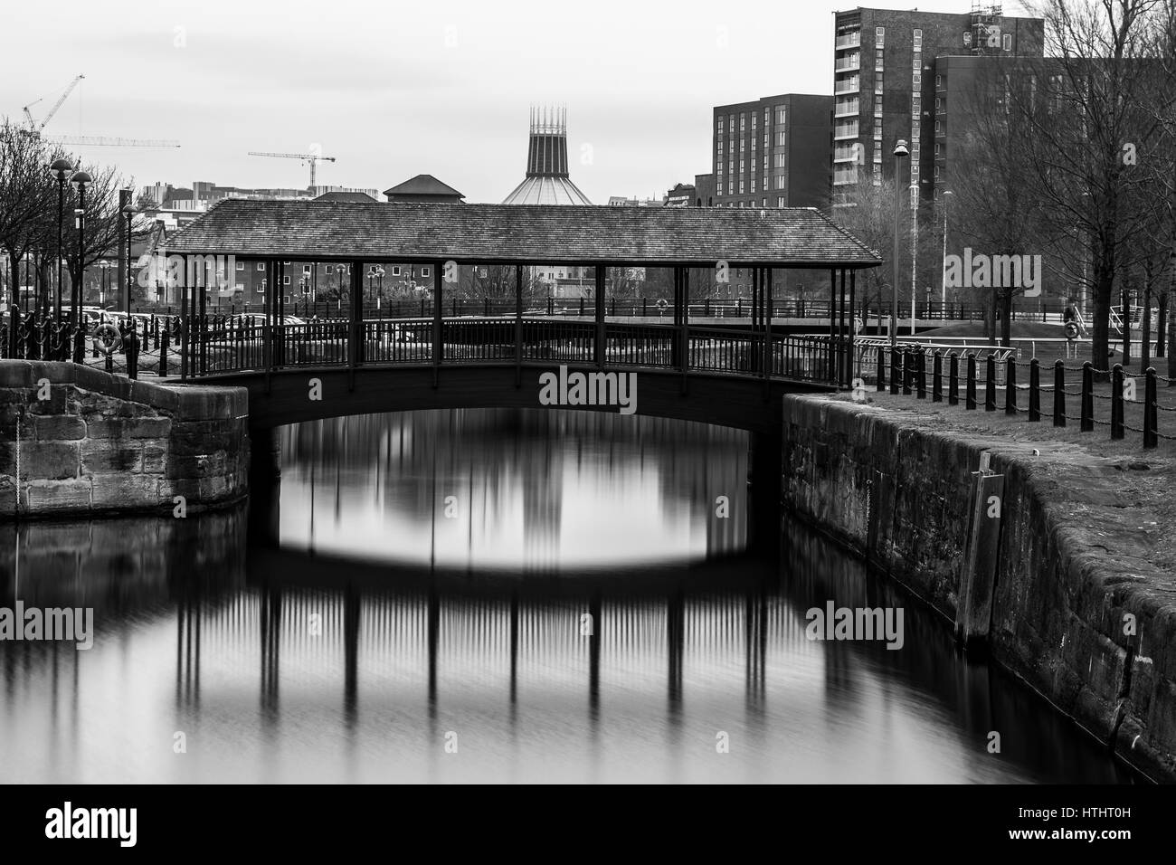 Die Metropolitan-Kathedrale & eine Fußgängerbrücke reflektieren auf dem Wasser der Herzöge Dock in Liverpool. Stockfoto