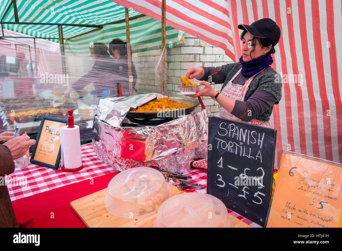 Eine Spanierin Stall Inhaber in einem UK Bauernmarkt dient einen Teil der dampfenden heißen Paella Stockfoto