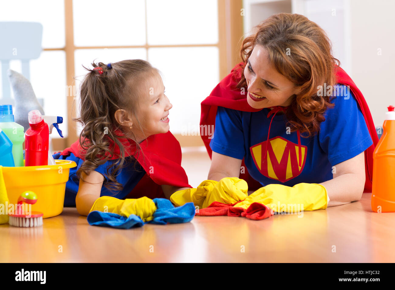 Schöne Mutter und Tochter süßes Kind gekleidet wie Superhelden. Frau und Kind bereit, die Reinigung des Hauses. Stockfoto