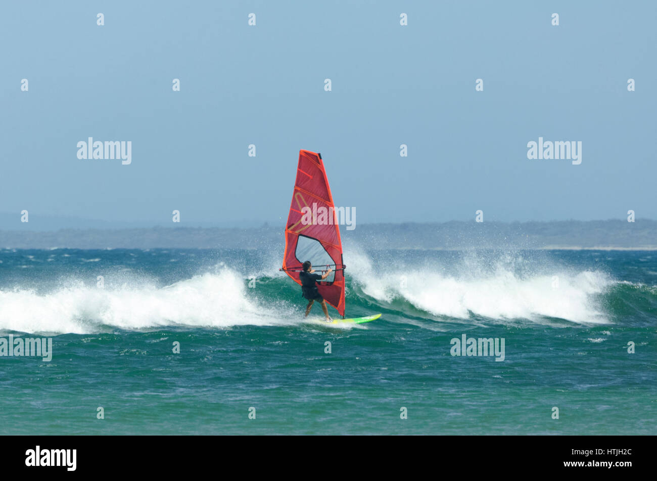 Windsurfer mit bunten Segel und Surfbrett am Seven Mile Beach, Gerroa, Illawarra Coast, New-South.Wales, NSW, Australien Stockfoto