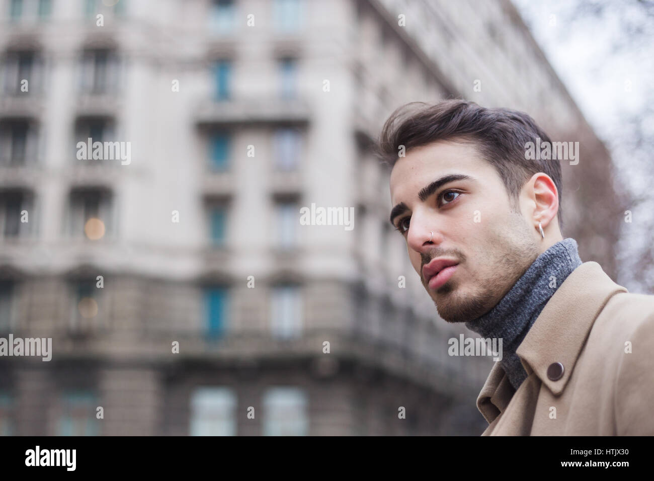 Schöner junger Mann mit kurzen Haaren posiert im urbanen Kontext Stockfoto