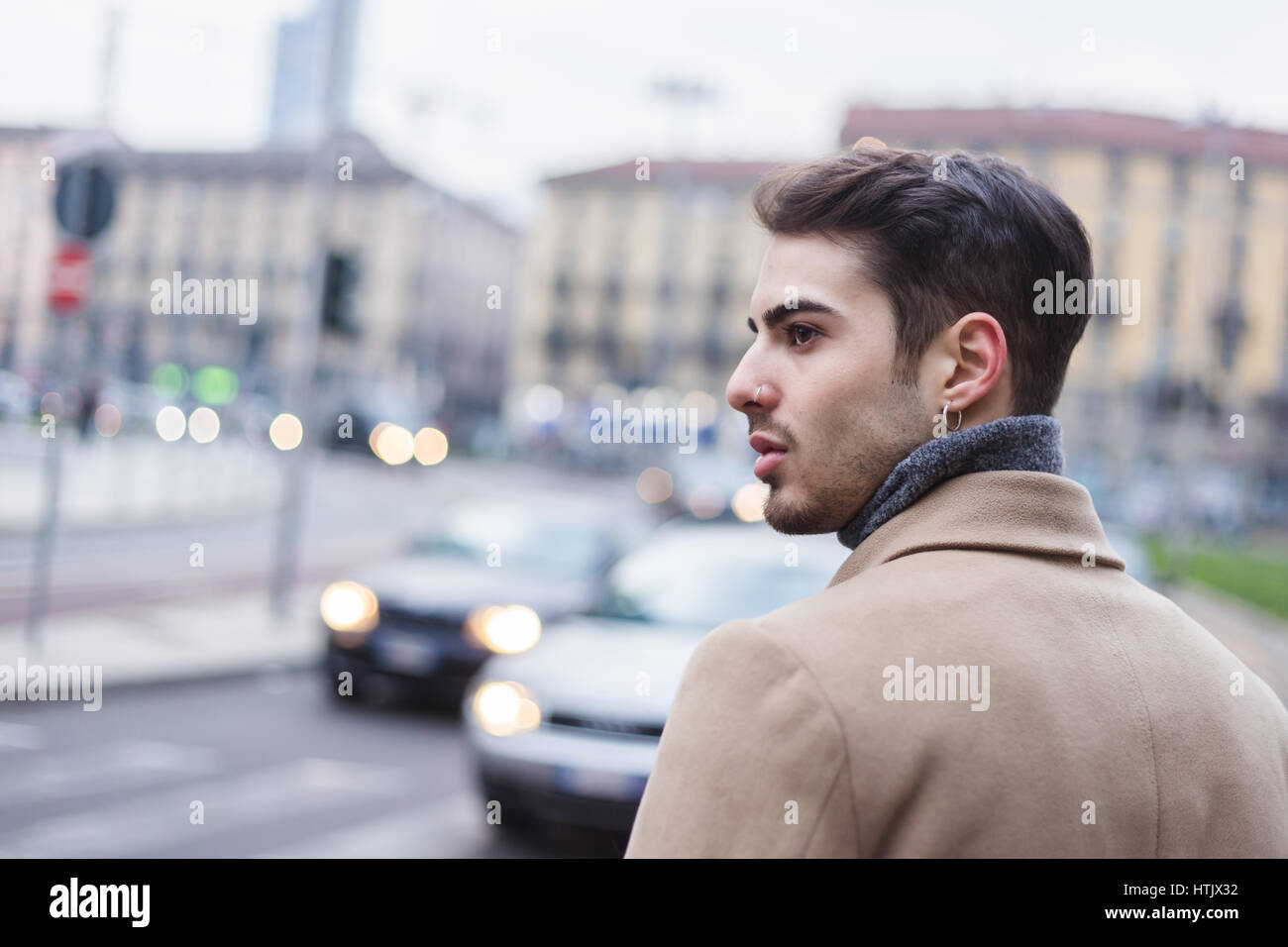 Schöner junger Mann mit kurzen Haaren posiert im urbanen Kontext Stockfoto