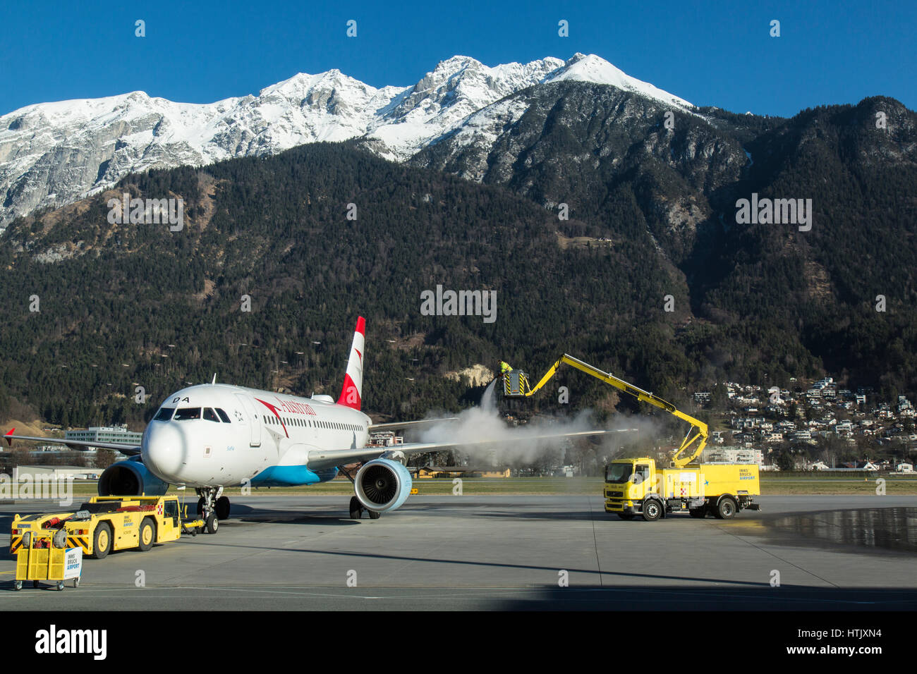 Ein Austrian Airlines Airbus A319 besprüht mit Enteiser vor dem Abflug am Flughafen Innsbruck, Österreich. Alpen im Hintergrund. Stockfoto