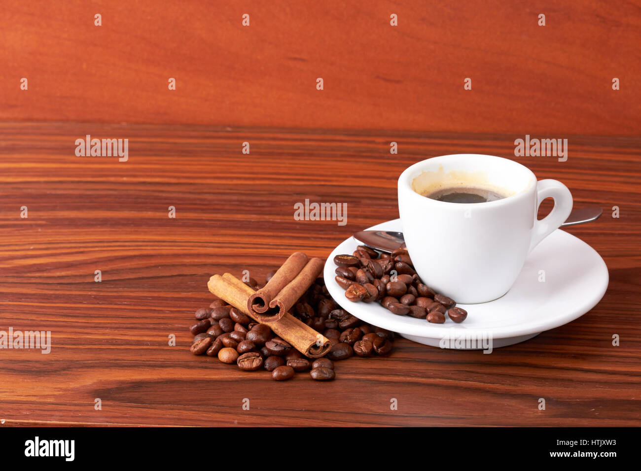 Tasse Kaffee mit Kaffeebohnen und Zimtstangen Stockfoto