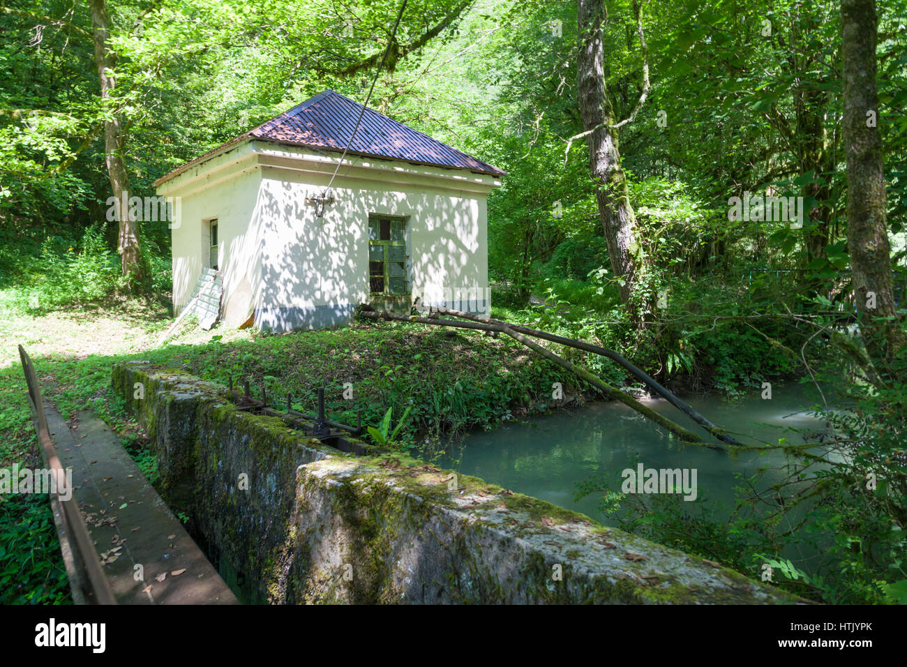Weißes Haus mit Wasseraufnahme am Ufer eines Baches in eine Forellenzucht in Abchasien Stockfoto