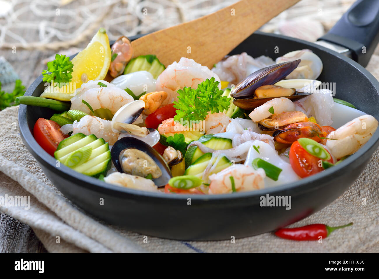 Gemischte frittierte Meeresfrüchte und frischem bunten Gemüse serviert in  einer eisernen Pfanne mit Scheiben Baguette mit Kräuterbutter  Stockfotografie - Alamy