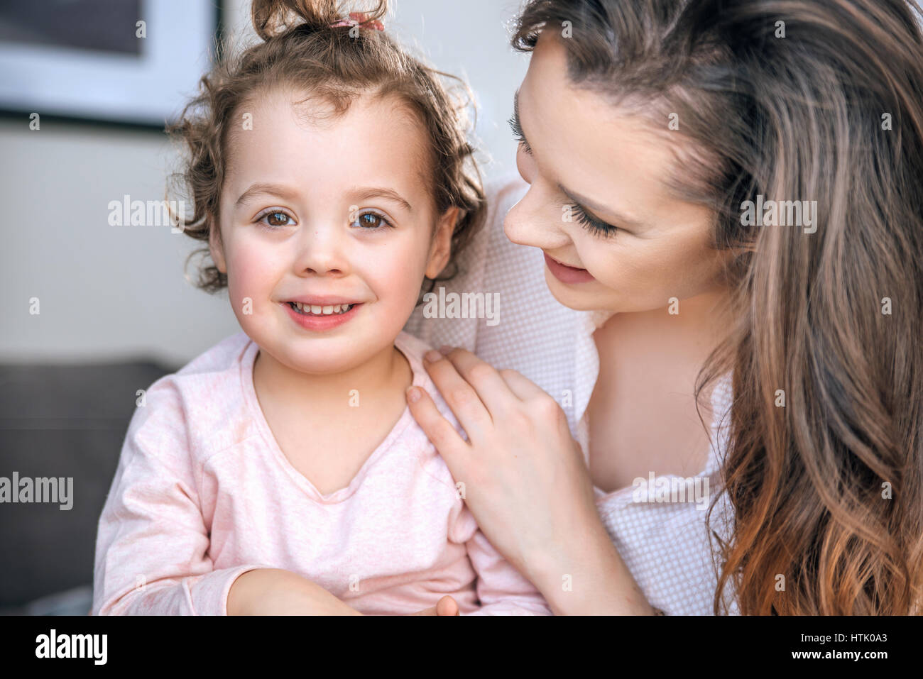 Attraktive junge Mutter umarmt ihre geliebte Tochter Stockfoto