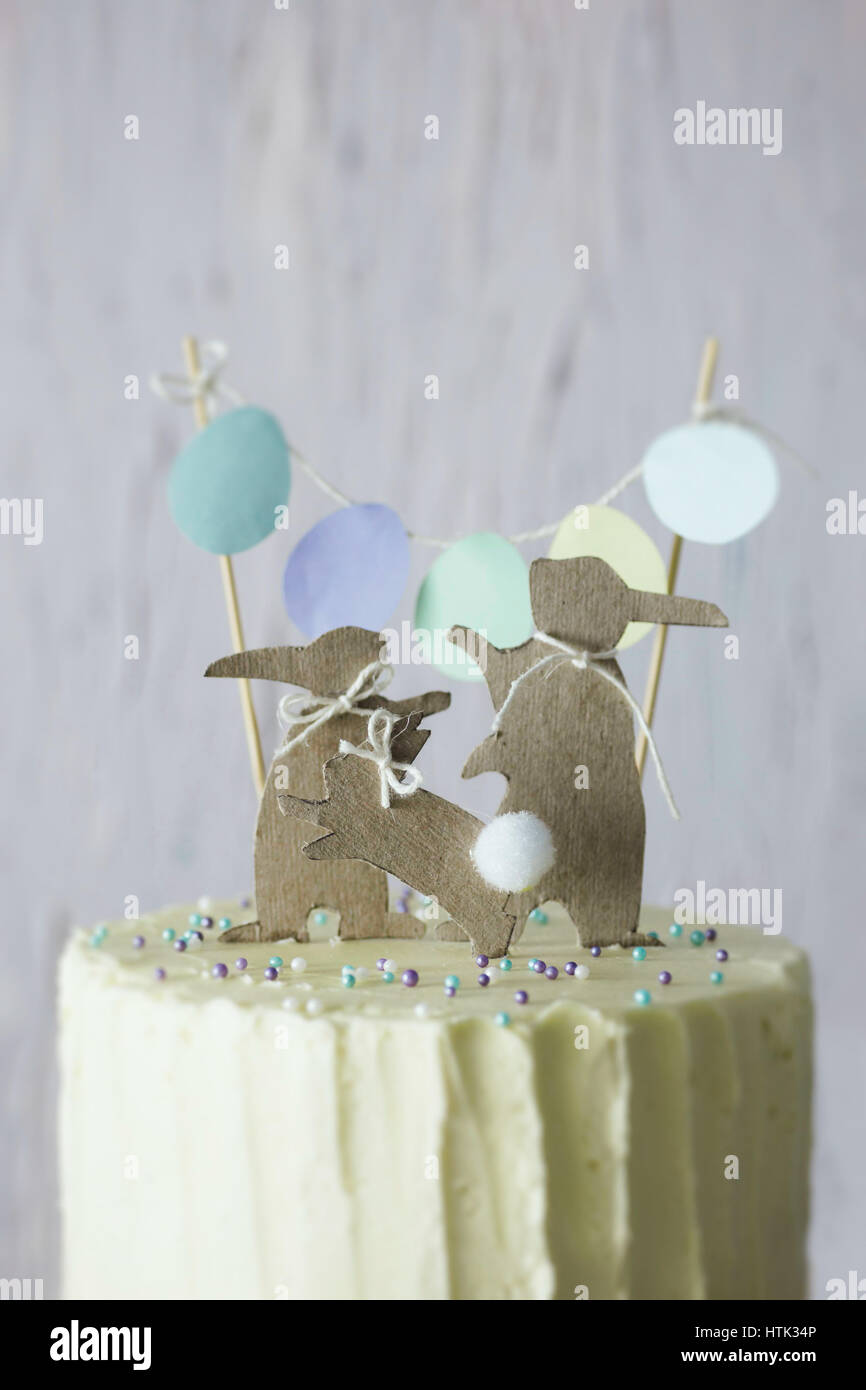 Unter dem Motto Hochzeit oder Geburtstag Osterkuchen, mit Papier-Kaninchen-Silhouetten als Kuchen Topper. Geringe Schärfentiefe. Stockfoto