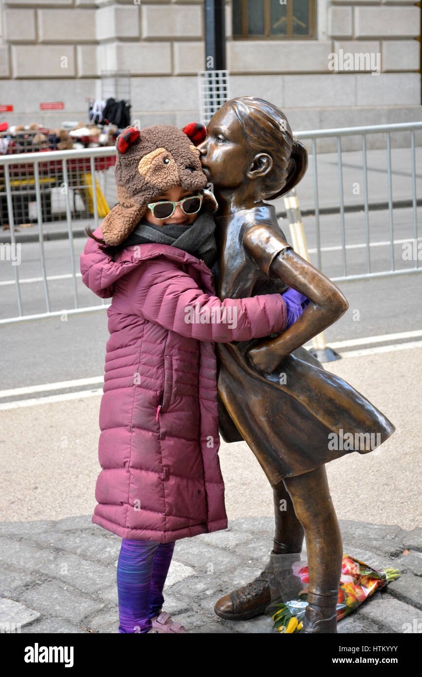 Junges Mädchen umarmt 'The Fearless Girl' Statue in Lower Manhattan. Stockfoto
