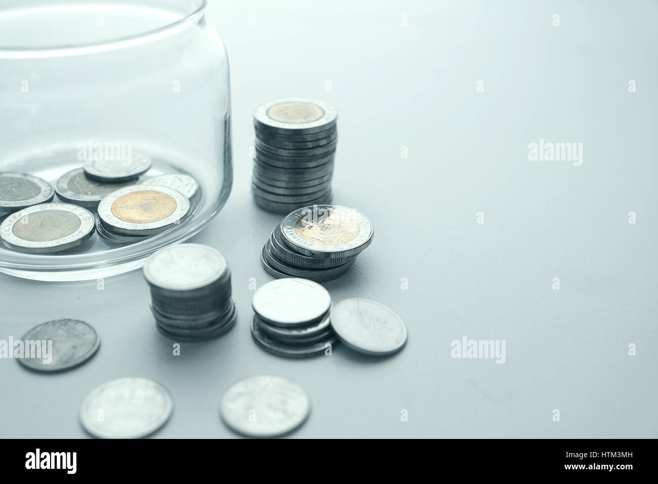 Münzen werden gestapelt und Glas Glas mit schwachem Licht. Spar-Konzept. Stockfoto