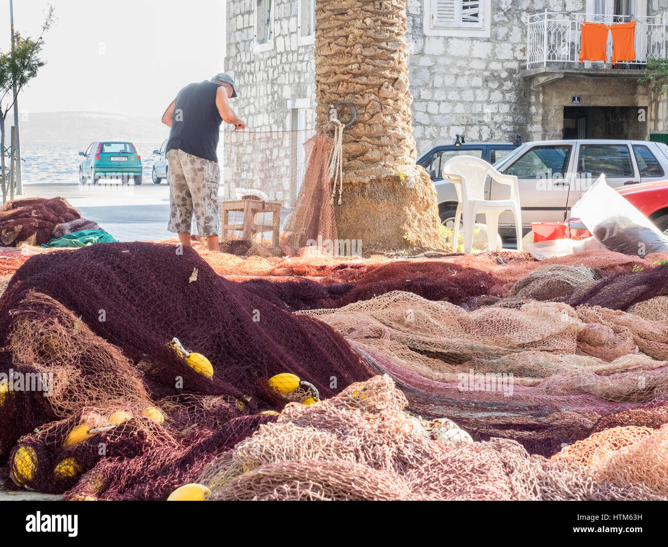 ein Fischer Flicken Nähen Reparatur seiner net Fischernetze am Hafen Hafen Kai Kroatien Stockfoto