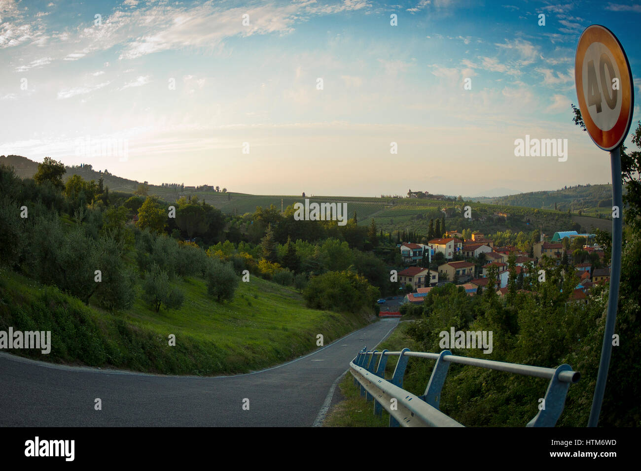Toskanische Landschaft mit einer schmalen Teerstraße führt zu unterzeichnen ein kleines Dorf eingebettet in grüne Hügel mit einem 40 km pro Stunde auf der rechten Seite Stockfoto