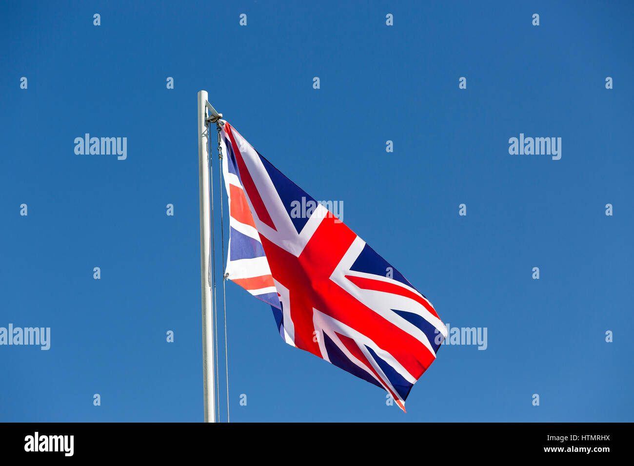 Britische Flagge am Fahnenmast vor blauem Himmel Stockfoto