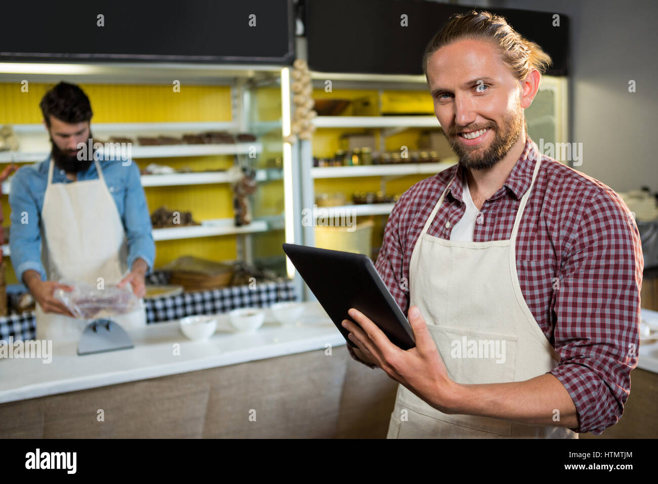 Porträt des Lächelns männlicher Angestellten mit digital-Tablette in der Nähe von Fleischtheke im Markt Stockfoto
