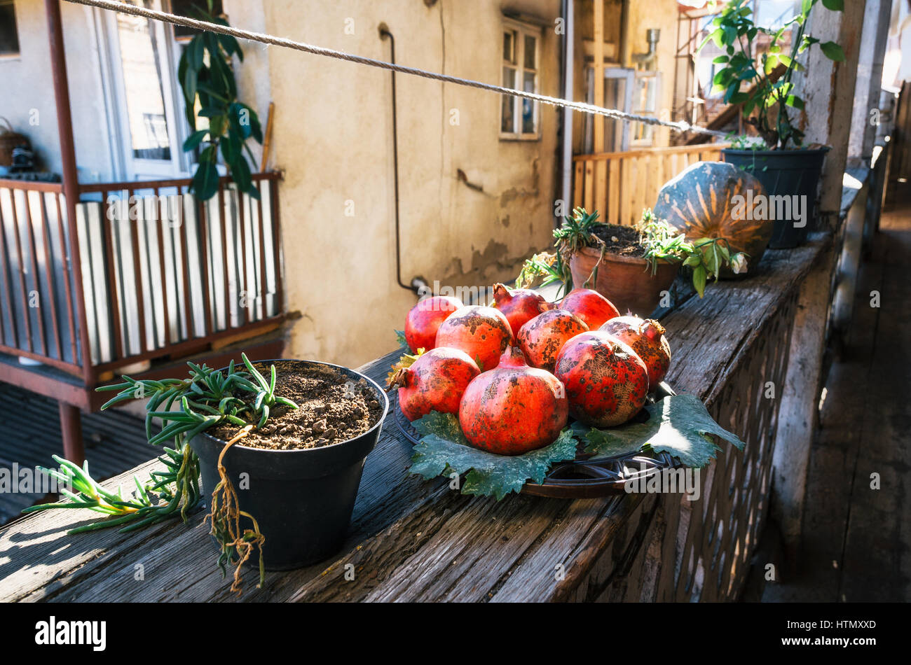 Granatapfel auf einem Teller auf der Terrasse an einem sonnigen Tag. Stillleben aus Granatäpfeln. Granatäpfel in einem georgianischen Gebäude. Stockfoto