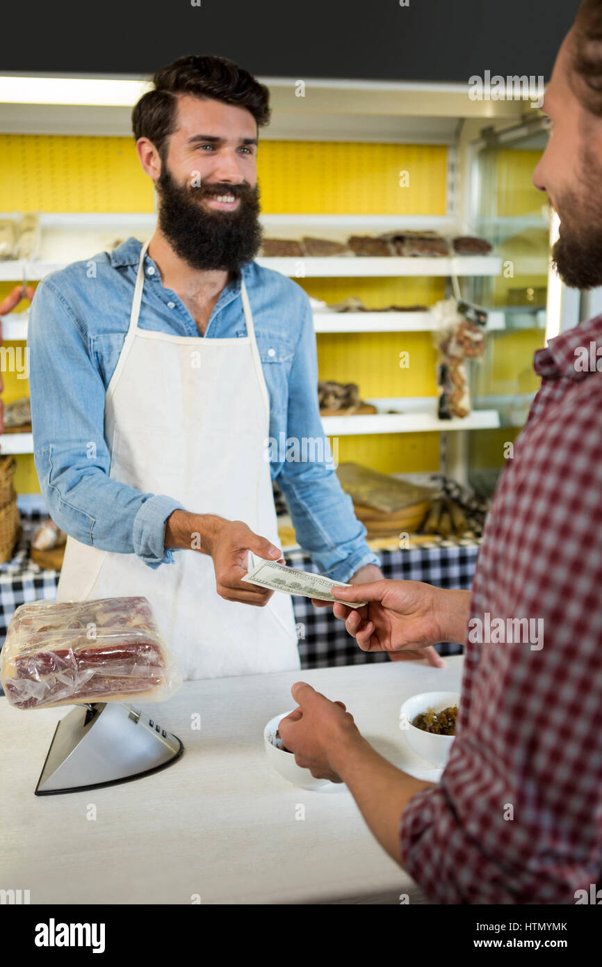 Kunden, die Zahlung der Rechnung in Bar an der Fleischtheke im Markt Stockfoto