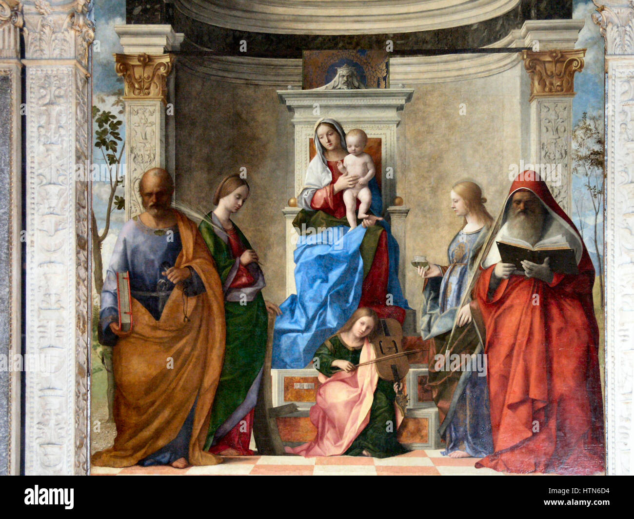 „Sacra Conversazione“ ist ein religiöser Altar des venezianischen Renaissance-Malers Giovanni Bellini. Das Werk zeigt die Jungfrau Maria mit Kind und Heiligen, die in einem heiligen Gespräch sind. Bellinis Verwendung von Farbe und Licht in diesem Gemälde veranschaulicht seine Beherrschung des Stils der Frührenaissance und hebt seine Beiträge zur religiösen und Renaissance-Kunst hervor. Stockfoto