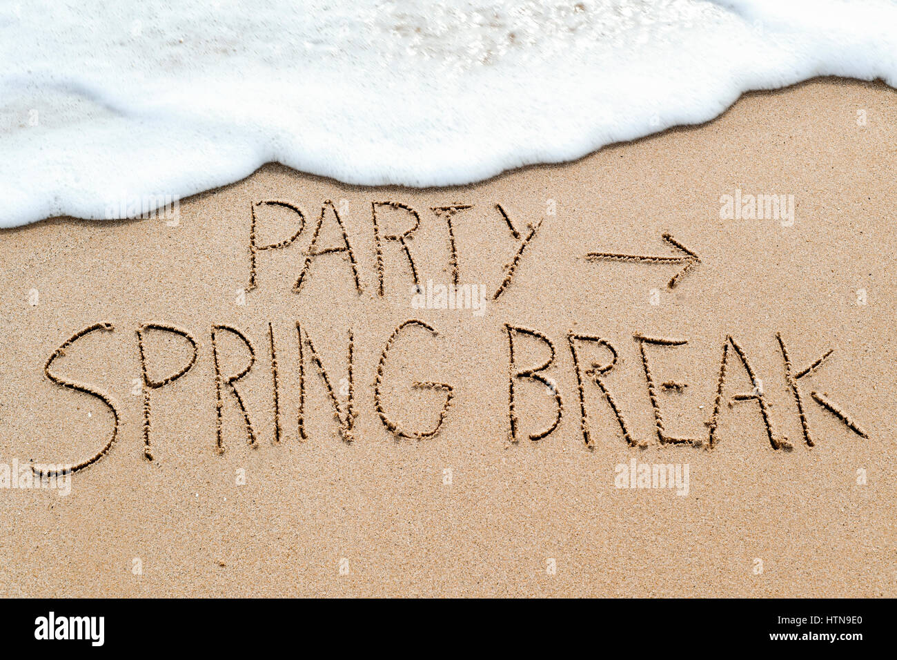 Nahaufnahme von einem Pfeil-Symbol und den Text Partei Frühlingsurlaub im nassen Sand an der Meeresküste, in einem Strand geschrieben Stockfoto