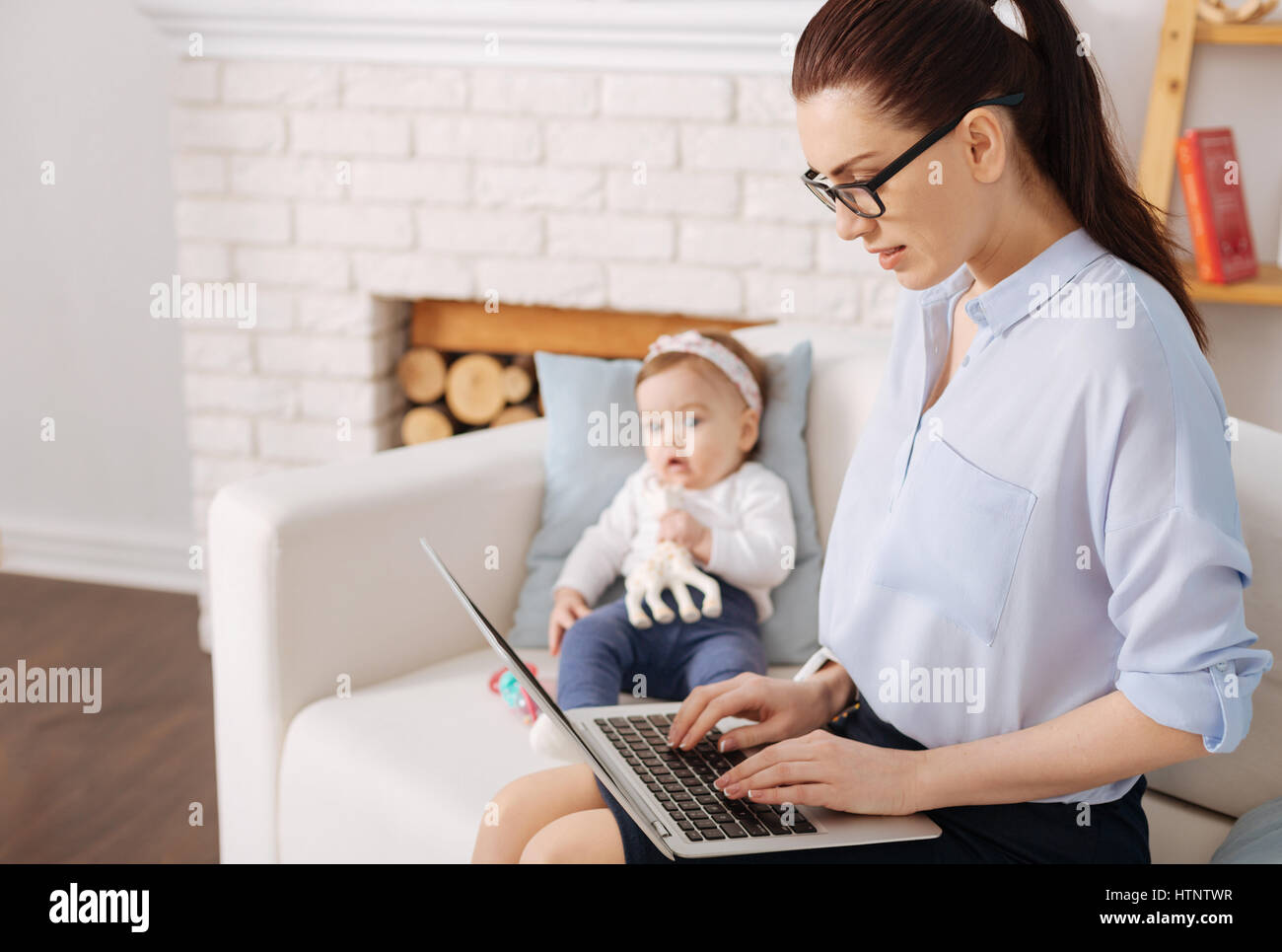 Praktischer Ansatz. Clevere unternehmungslustige fürsorgliche Mutter, die Ausgaben ihrer Elternzeit zu Hause mit ihrem Kind während noch Zeit finden für ihre Karriere Stockfoto