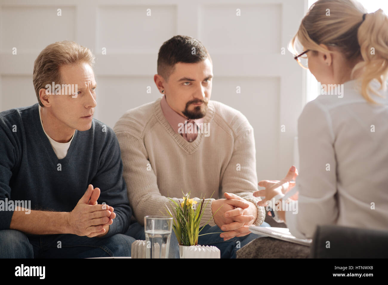 Wir hören. Ernsthafte ängstlich nachdenklich schwules Paar mit Blick auf ihre Therapeutin und hören sie bei dem Versuch, ihre Beziehung zu retten Stockfoto