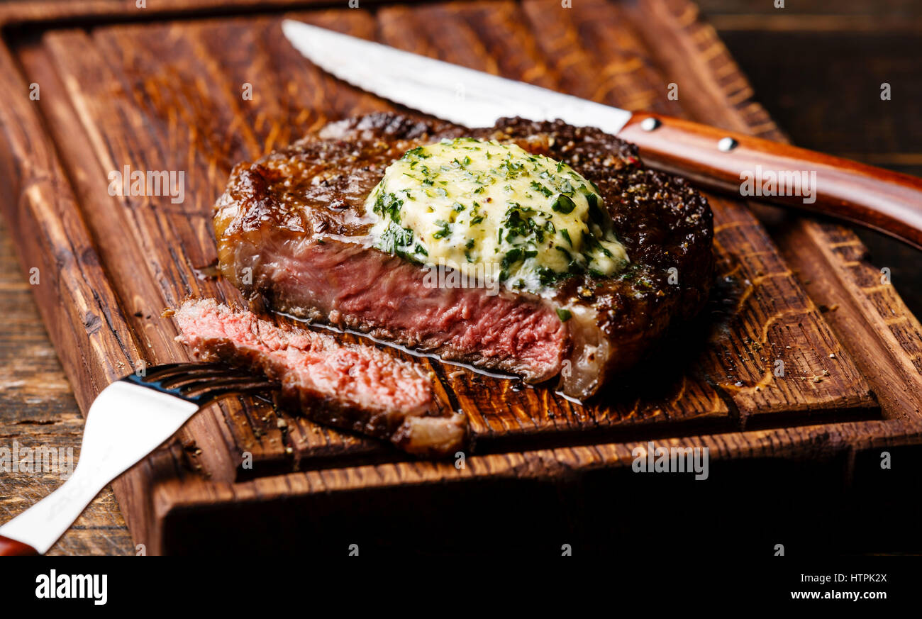 Medium rare Steak Ribeye mit Kräuterbutter auf Schneidebrett Portionsgröße gegrillt Stockfoto