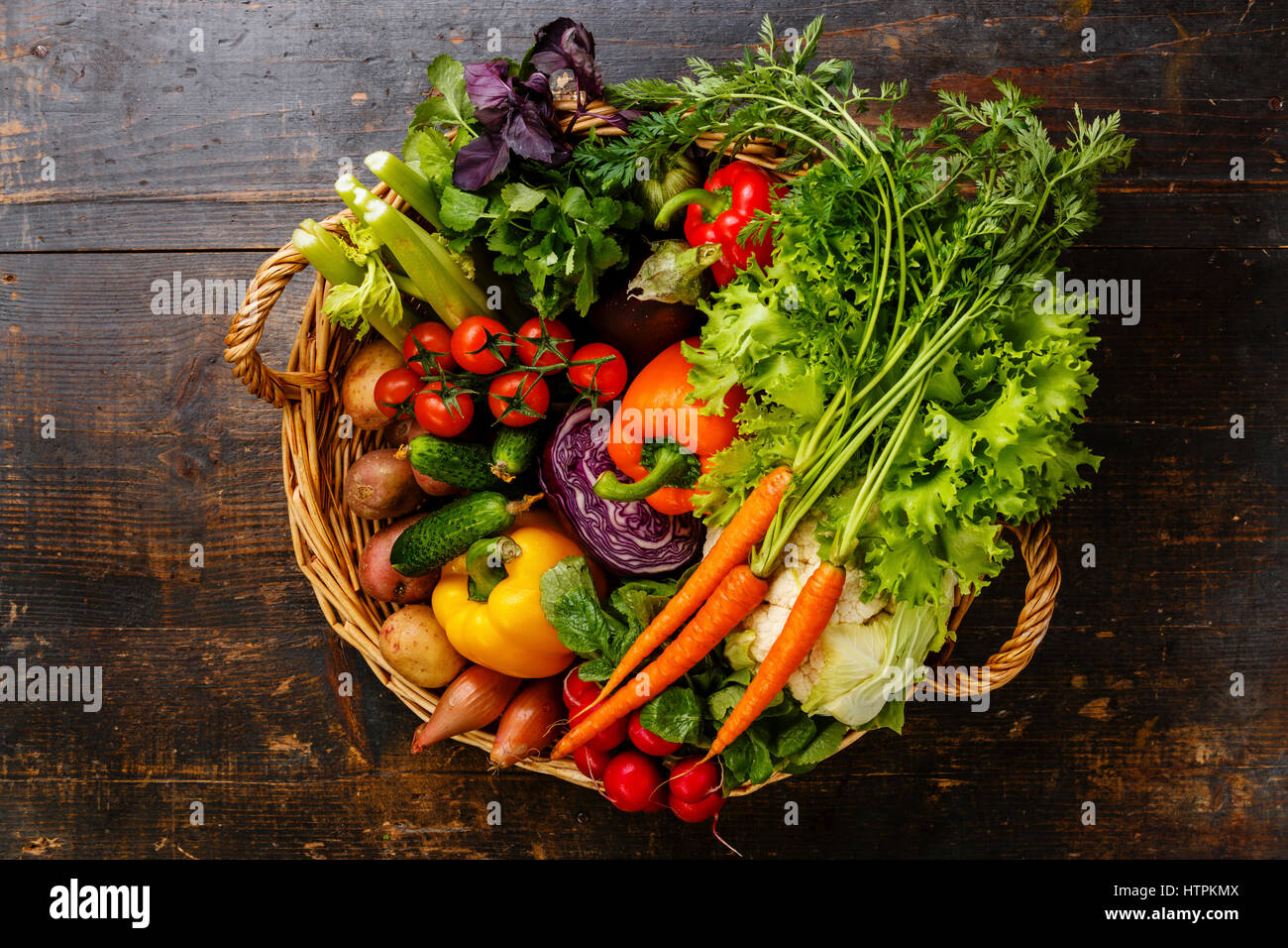 Frisches Gemüse im Korb auf hölzernen Hintergrund Stockfoto