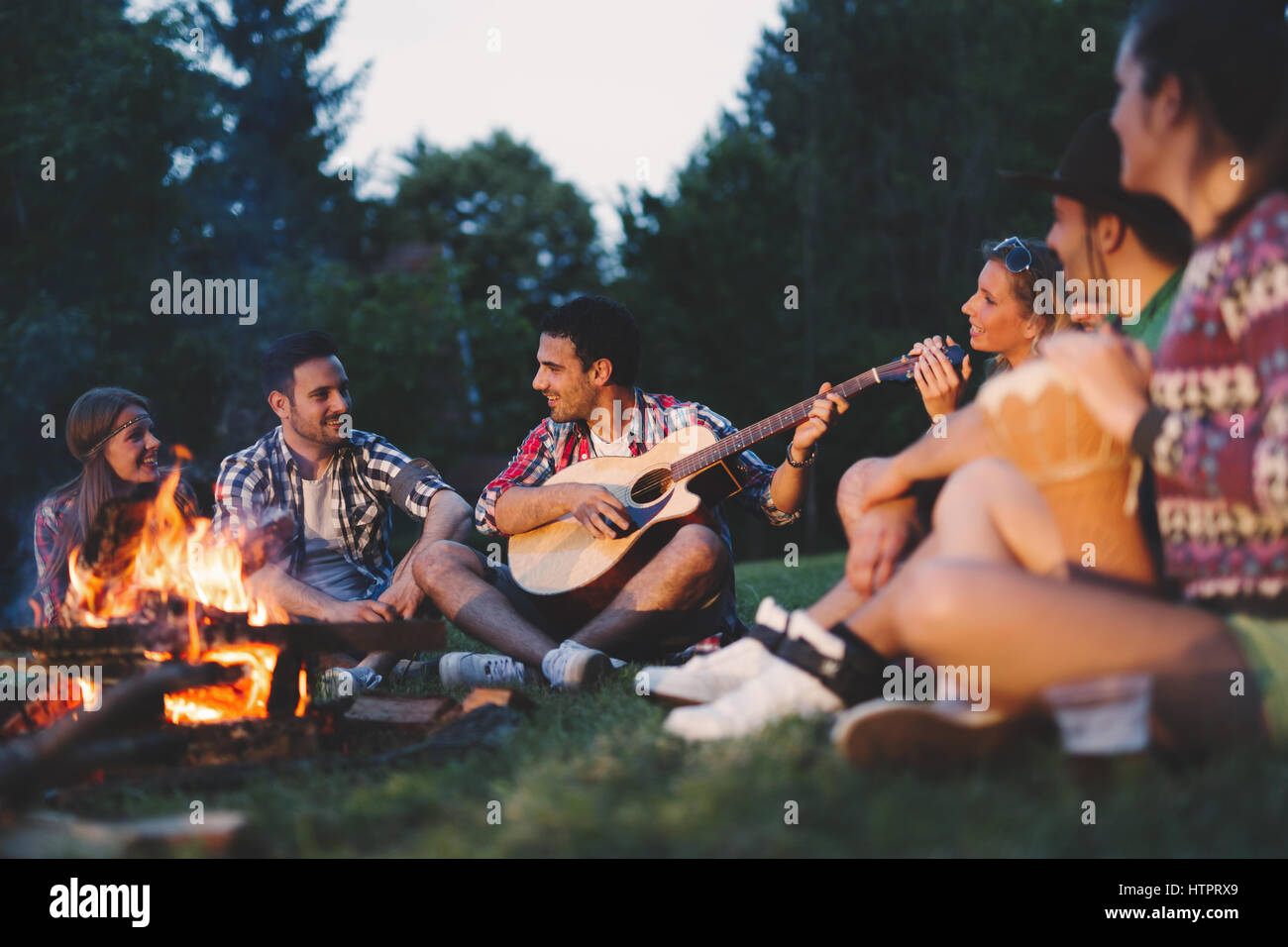 Glückliche Freunde spielen Musik und Lagerfeuer in der Natur zu genießen Stockfoto