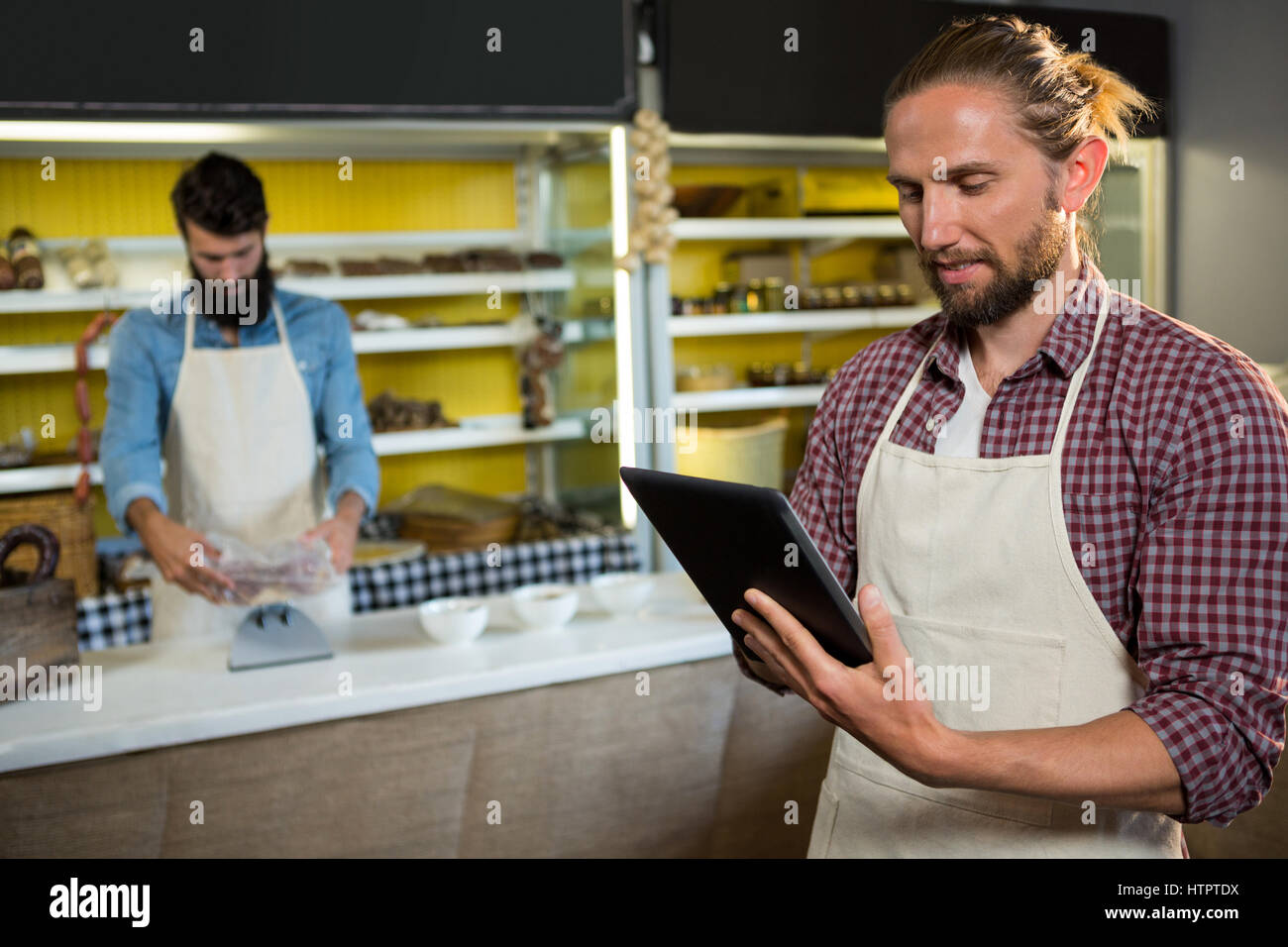Männliche Mitarbeiter mit digital-Tablette in der Nähe von Fleischtheke im Markt Stockfoto