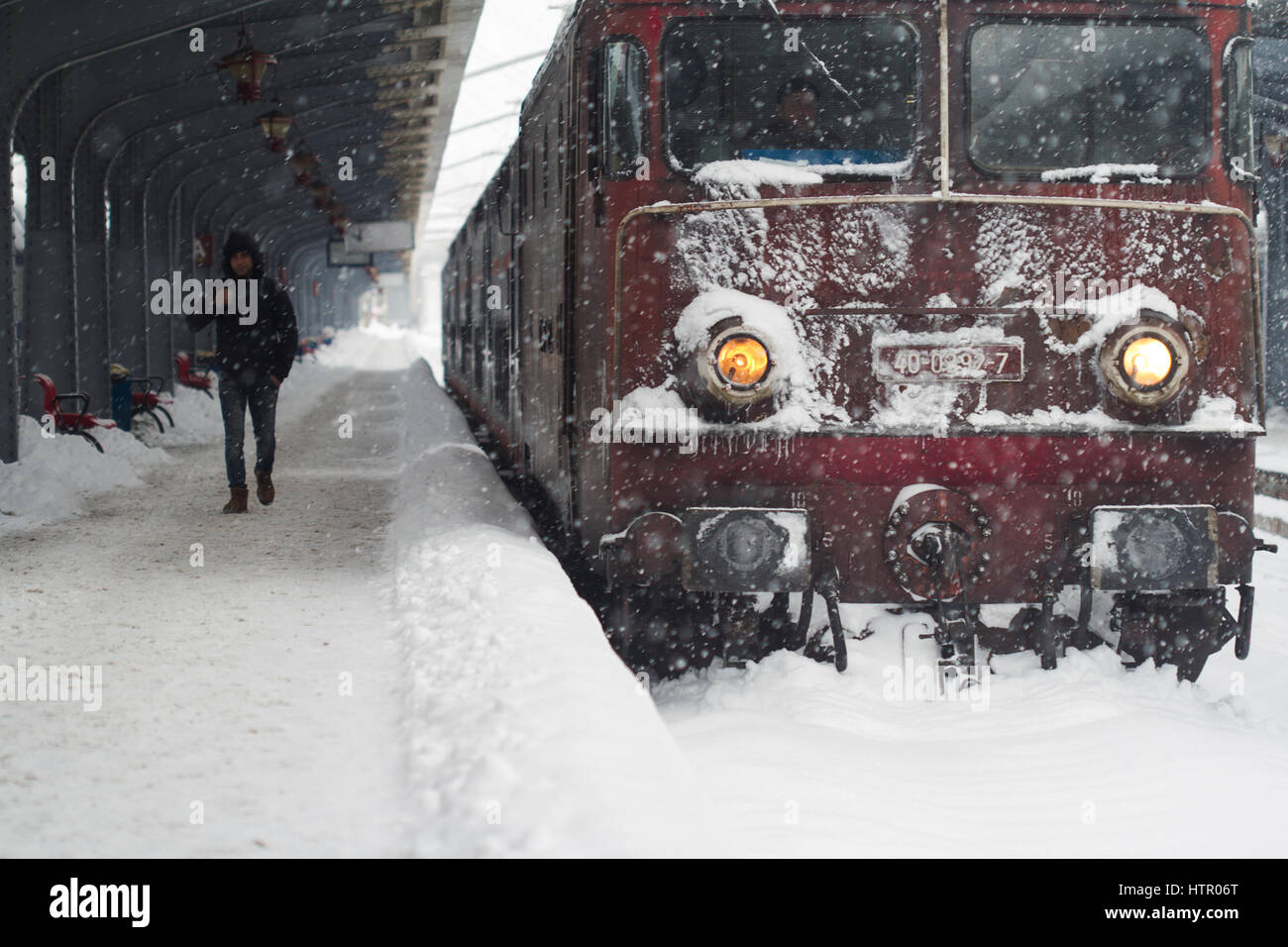 Bukarest, Rumänien - 7. Januar 2017: Vorderansicht der kaukasischen Jüngling, vorbei an einem frostigen Passagier Zug Lokomotive in einen ordentlichen Schneesturm in Stockfoto