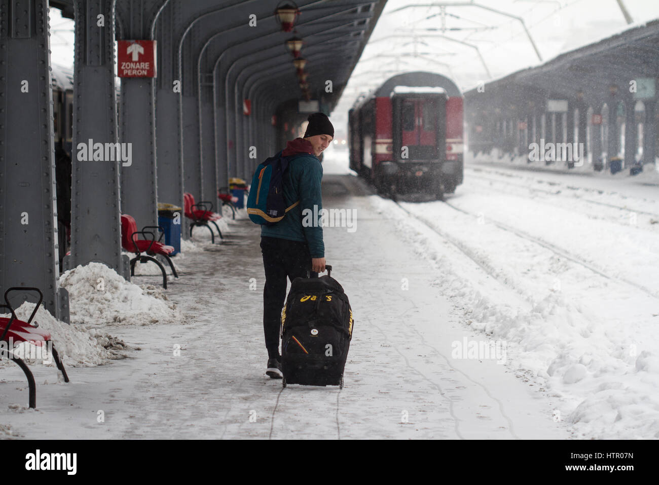 Bukarest, Rumänien - 7. Januar 2017: Rückansicht des kaukasischen Jüngling mit seinem Wagen auf seinem Zug während einen ordentlichen Schneesturm in Bukarest N Stockfoto