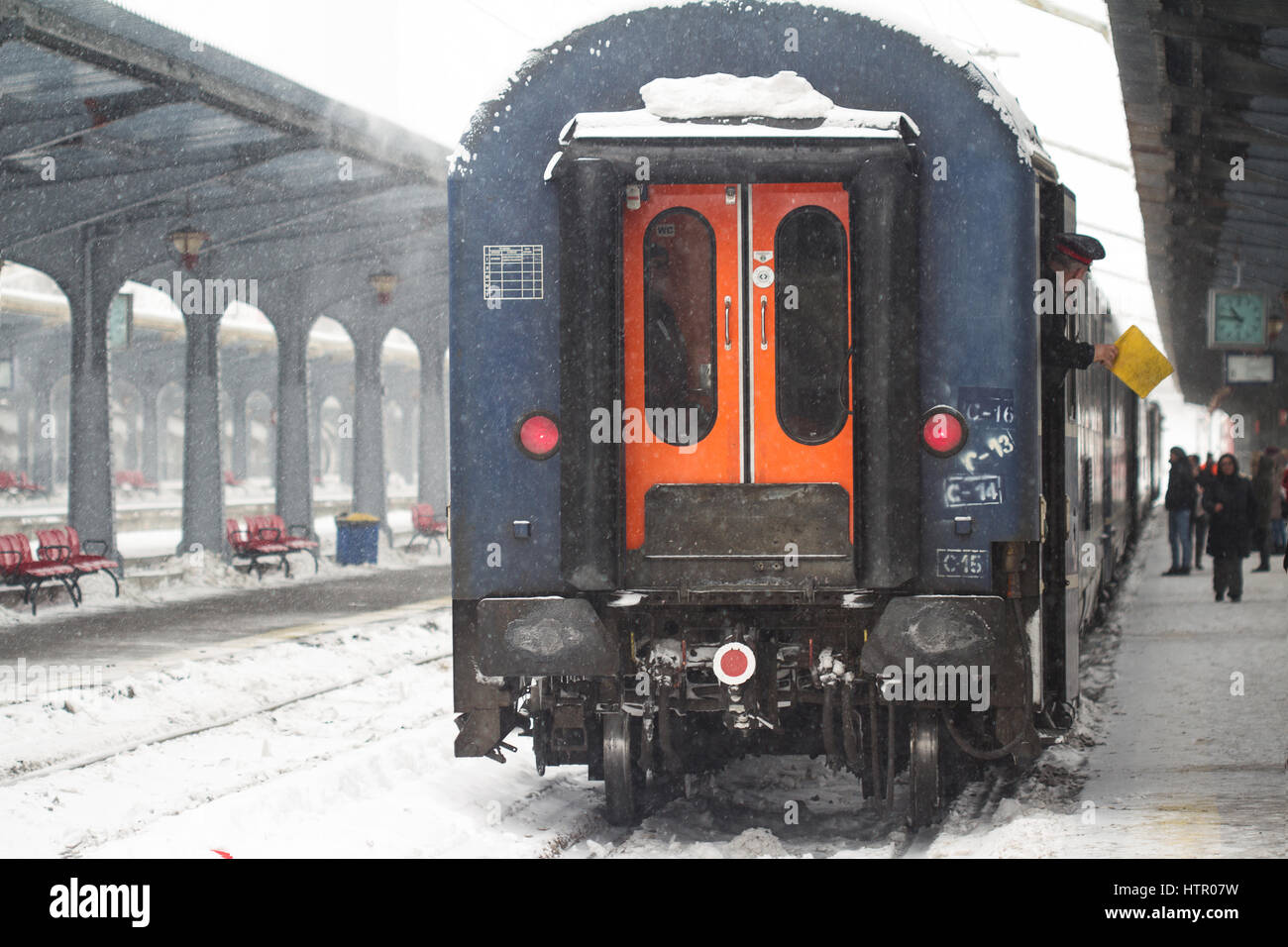 Bukarest, Rumänien - 7. Januar 2017: Rückansicht der Zugführer mit einer gelben Fahne, die Abfahrt Signal während einer ordentlichen Schneesturm in Bucha Stockfoto