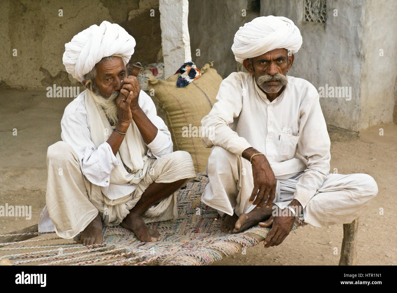 Bishnoi Männer rauchen Pfeife im ländlichen Dorf in der Nähe von Jodhpur, Rajasthan, Indien Stockfoto