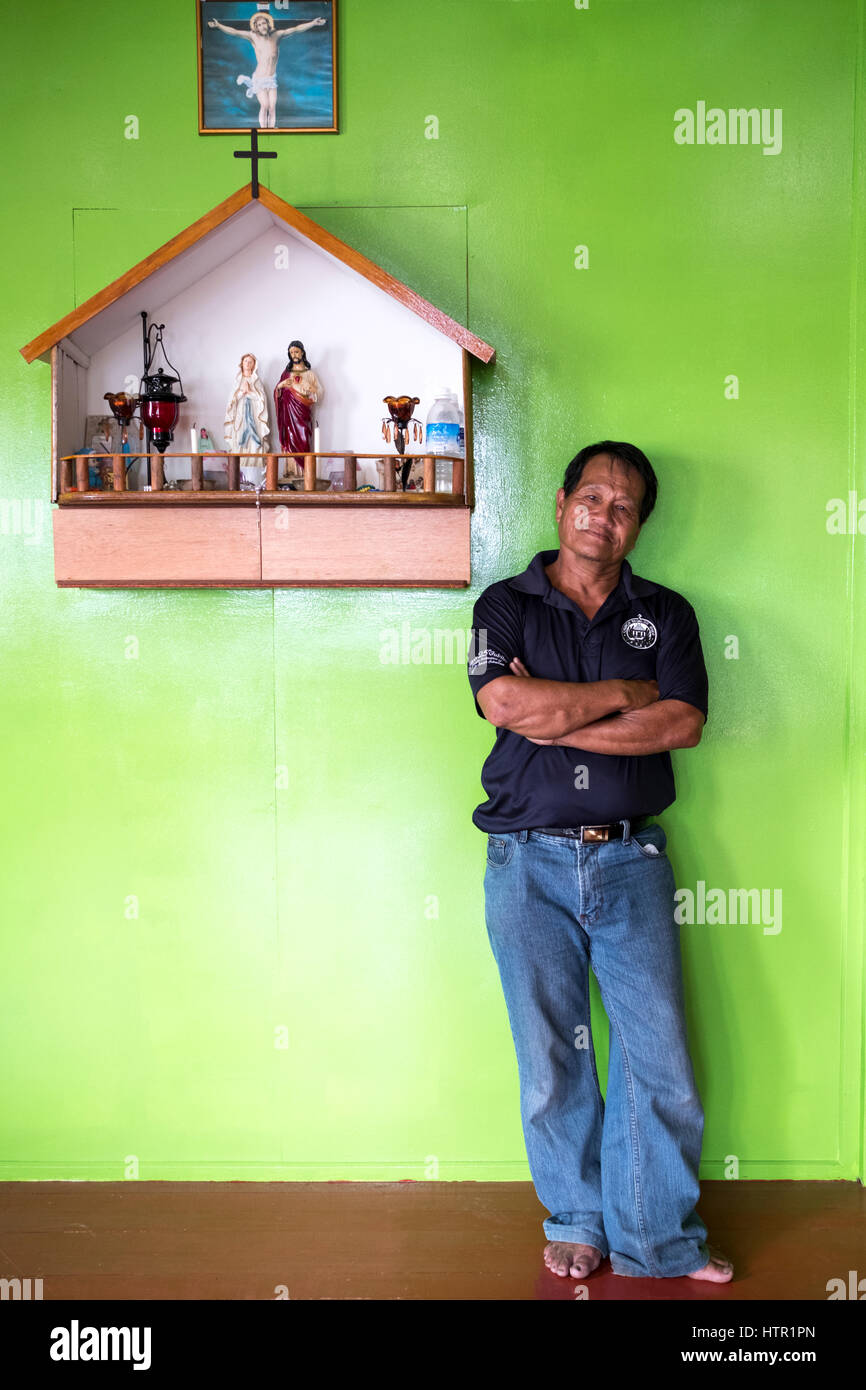 Cornelius Wong steht vor christlichen Symbole, die hängen an der Wand seines Hauses in Dalat, Sarawak, Malaysia Stockfoto