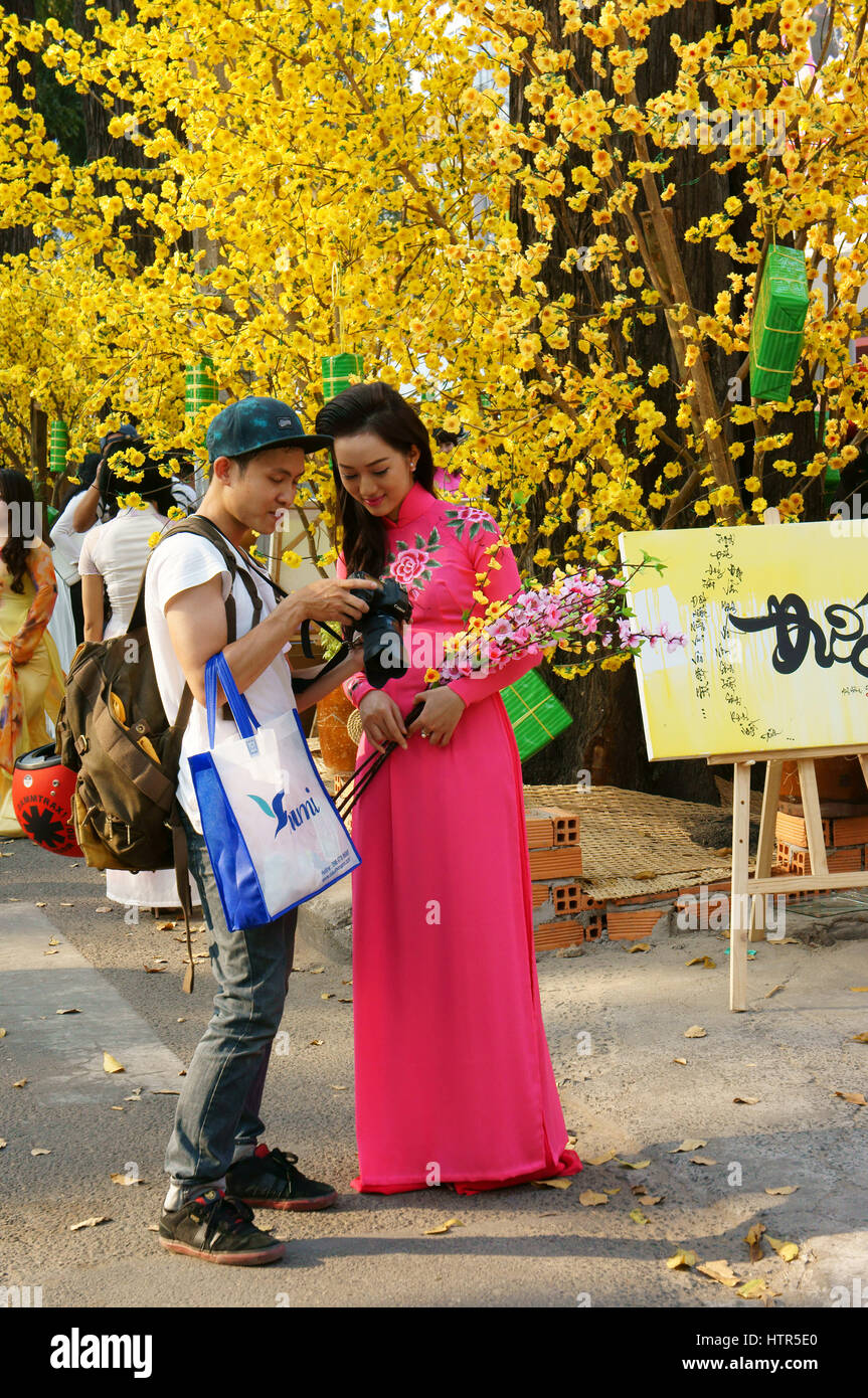 HO CHI MINH CITY, VIET NAM - FEB 7: Atmosphäre der Frühling mit bunten Szene in Saigon Street, Vietnamesin in Ao Dai, posiert neben Blume Stockfoto