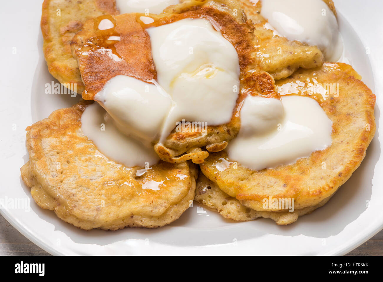 kleine individuelle Scotch Pfannkuchen serviert auf einem weißen Teller mit Joghurt und Honig Stockfoto