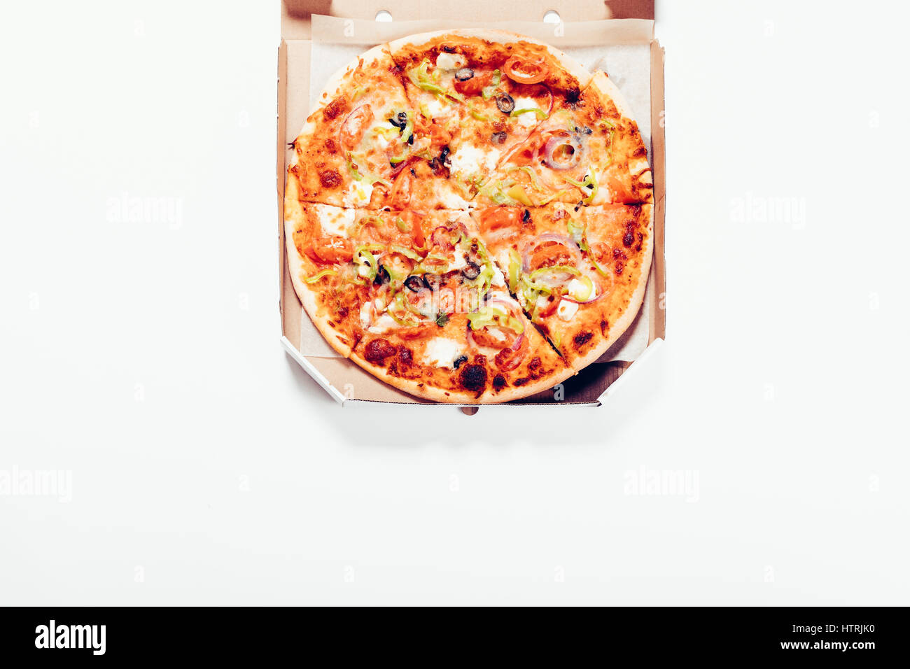 Pizza in einer Box liegt auf einem weißen Tisch, Ansicht von oben Stockfoto