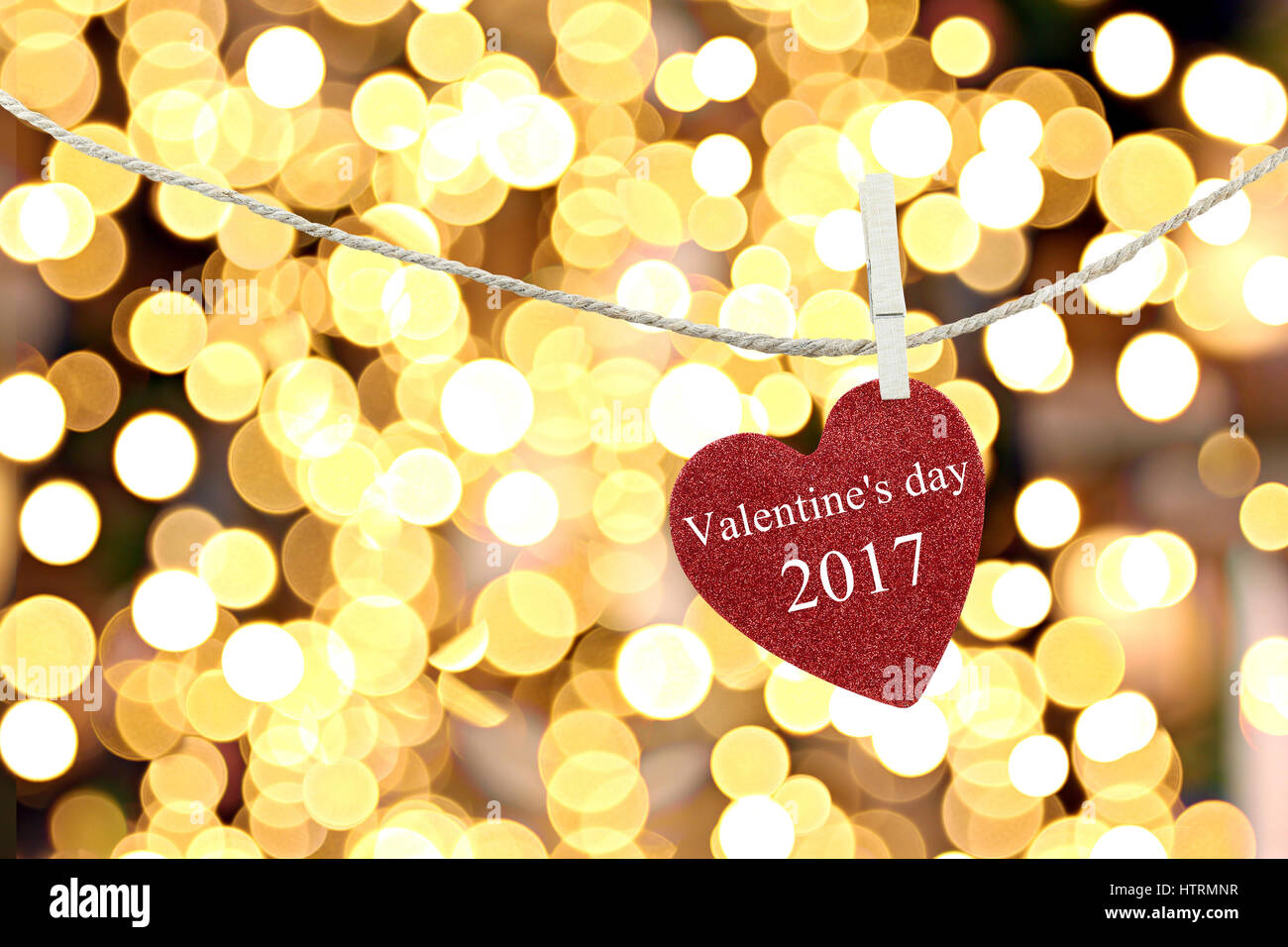 Red Heart auf Hanfseil aufgehängt und Text Happy Valentine Tag 2017 auf abstrakte gelbe Hintergrundfarbe Boken. Stockfoto