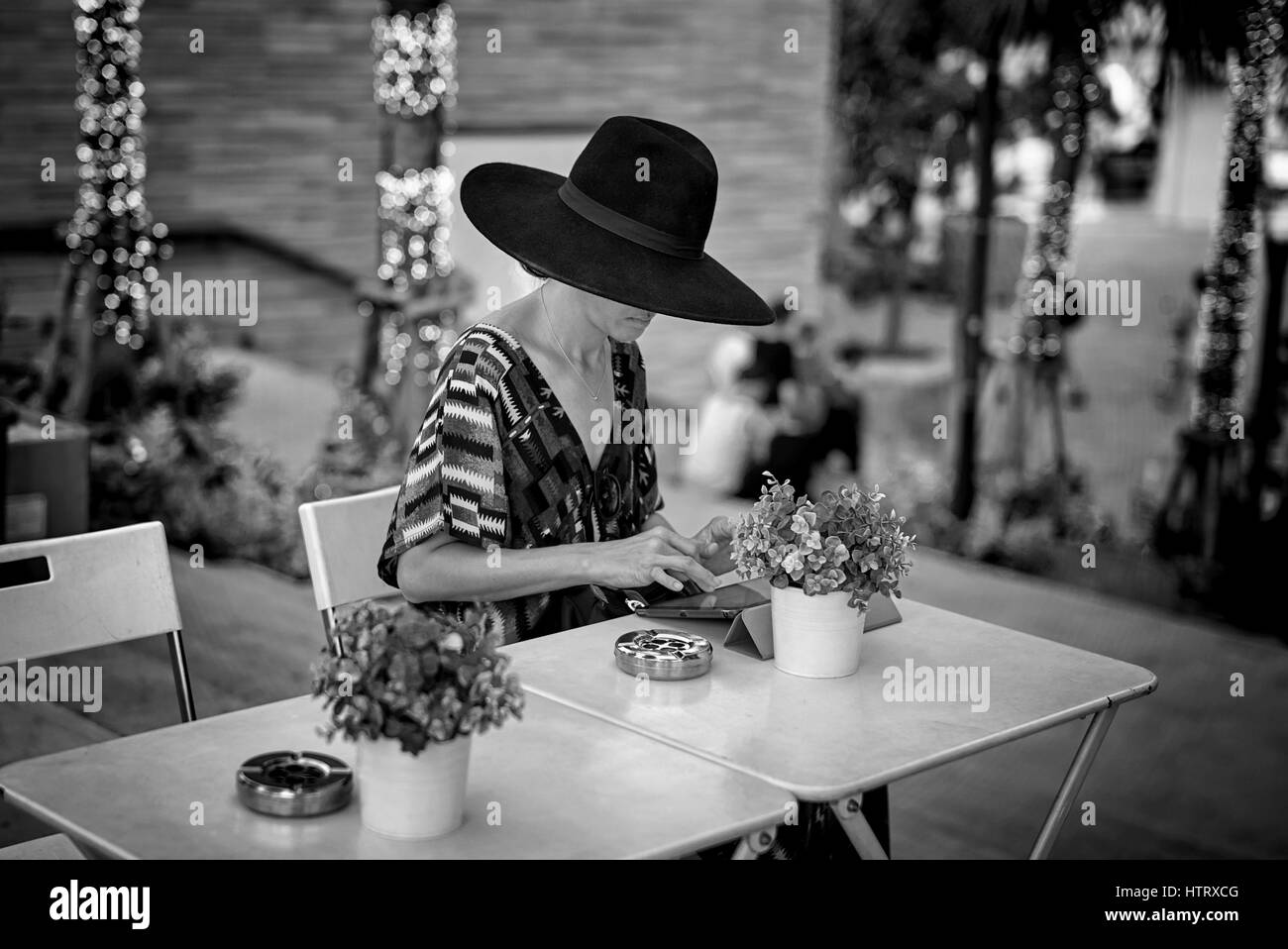Frau alleine im Freien mit einem iPad und tragen einen großen schwarzen Hut. Frau alleine im Freien. Südostasien die Schwarz-Weiß-Fotografie Stockfoto