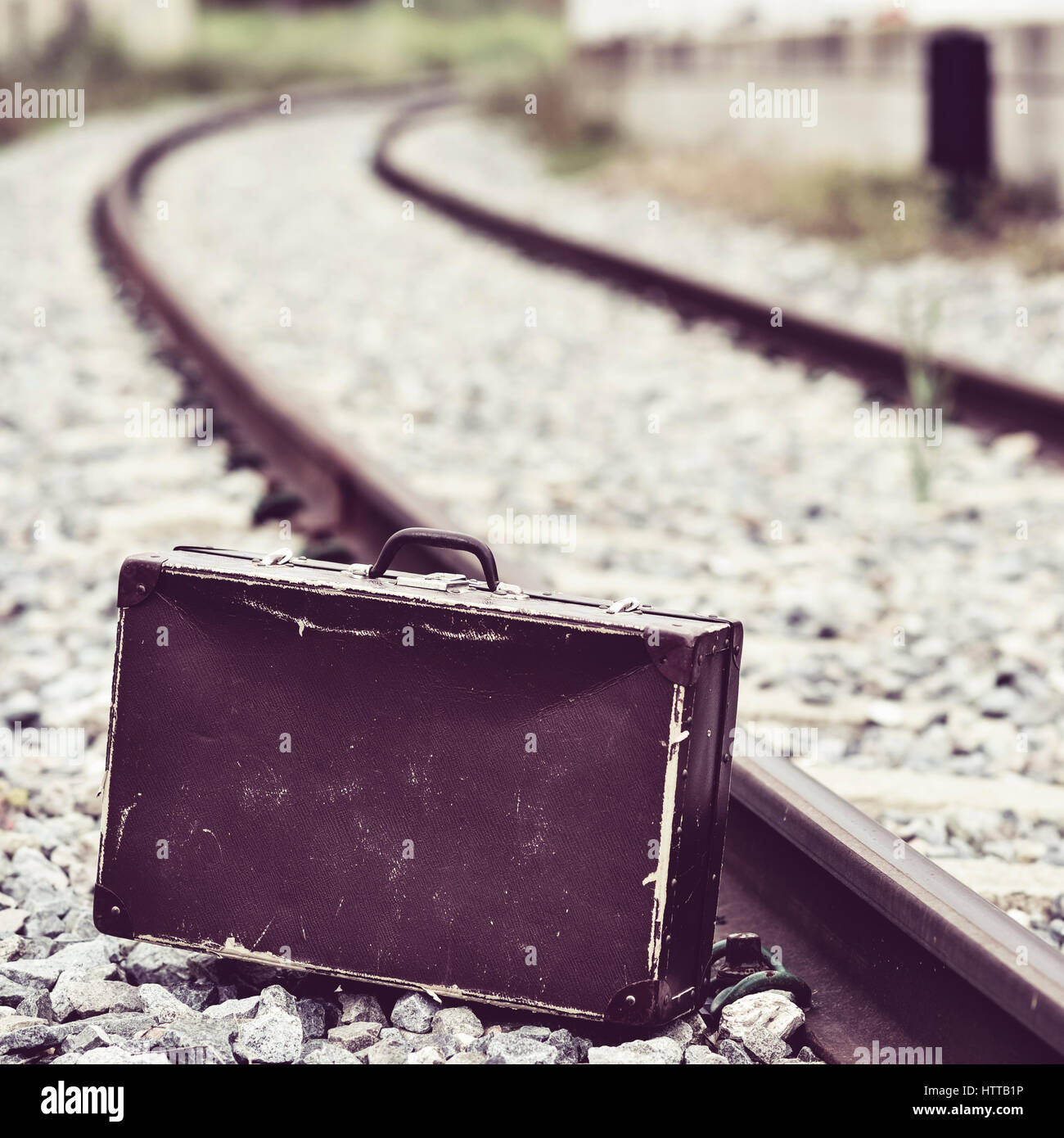 einen alten braunen Koffer neben den Bahngleisen Stockfoto