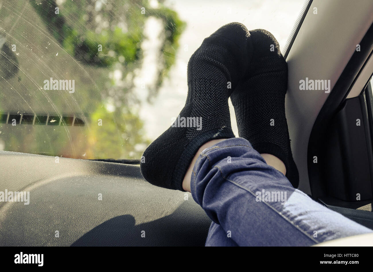 Füße auf dem Armaturenbrett des Autos mit schwarzen Socken. Stockfoto