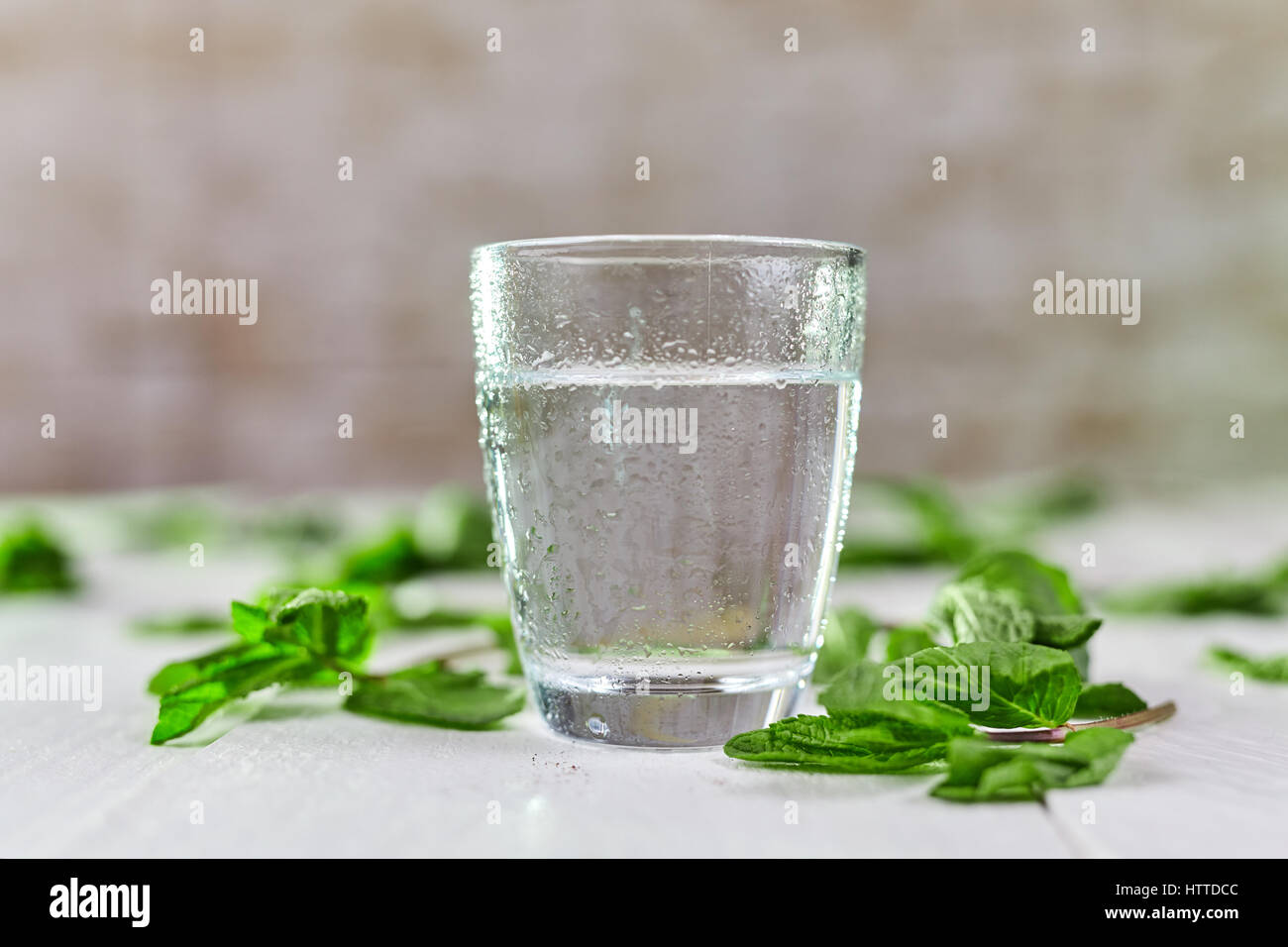 Glas frisches kaltes Wasser mit grüner Minze auf weißen Tisch Stockfoto