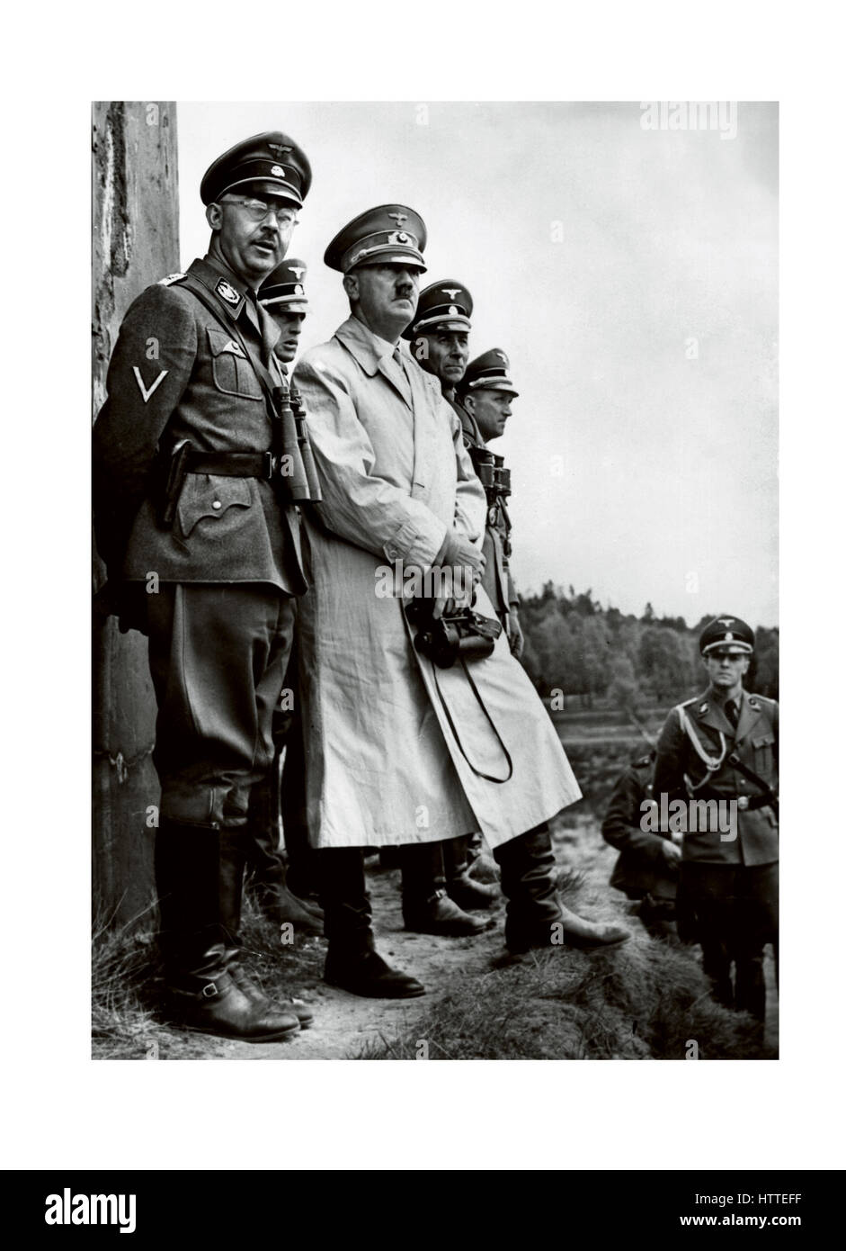 Adolf Hitler aus den 40er Jahren trägt einen Trenchcoat und ein Fernglas, mit Heinrich Himmler Waffen SS und hochrangigen Wehrmachtoffizieren Stockfoto