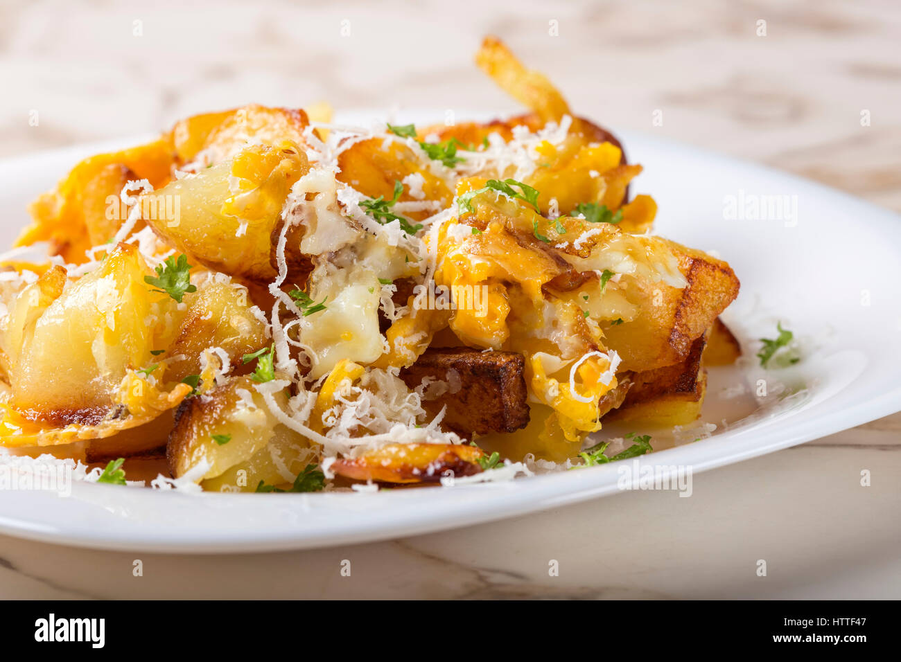 Pommes Frites mit zerschlagenen Eiern und Parmesan mit Kräutern auf weißen Teller Stockfoto