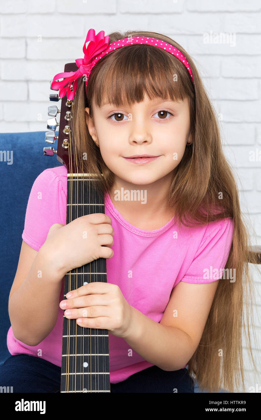 Kleines Mädchen umarmt eine Gitarre Stockfoto